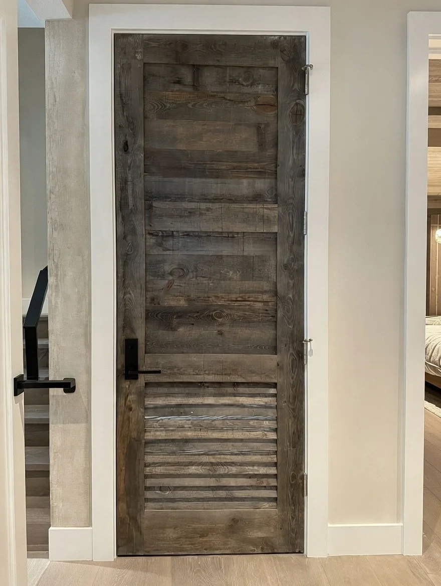 Interior view of a rustic wooden door with horizontal slats and black hardware, set within a white door frame.