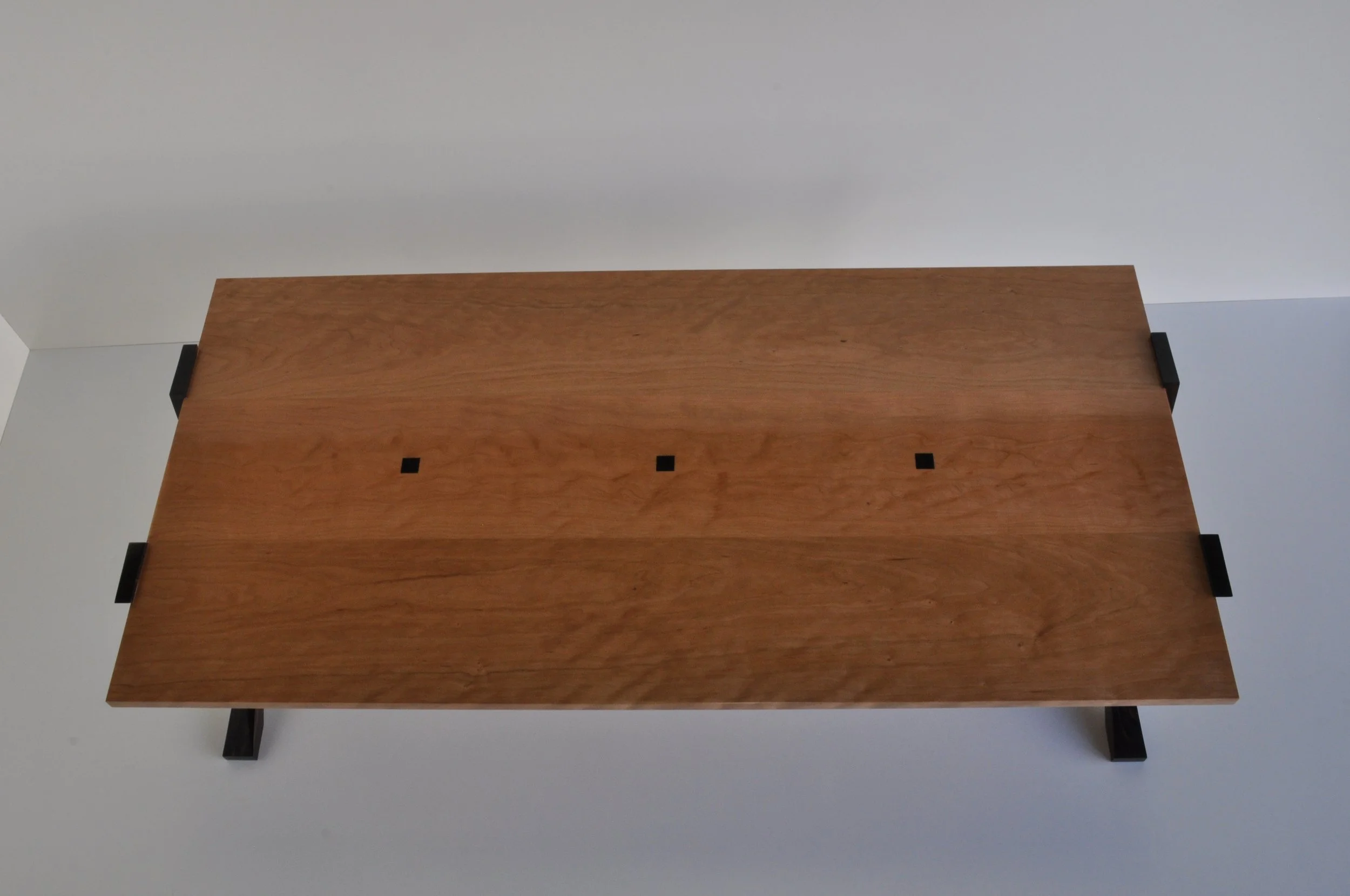 A wooden table with black legs viewed from above against a light background.