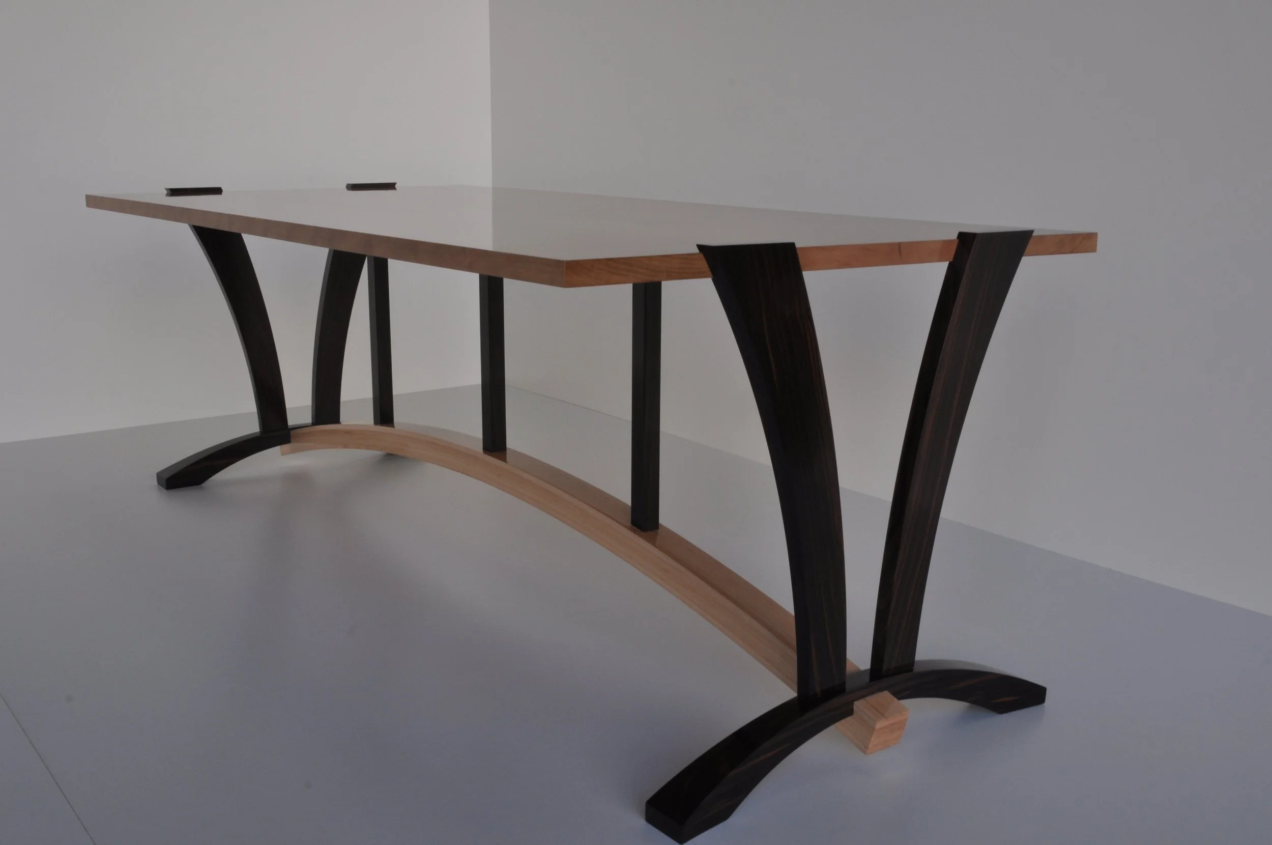 Modern wooden table with curved black legs and a light-colored tabletop