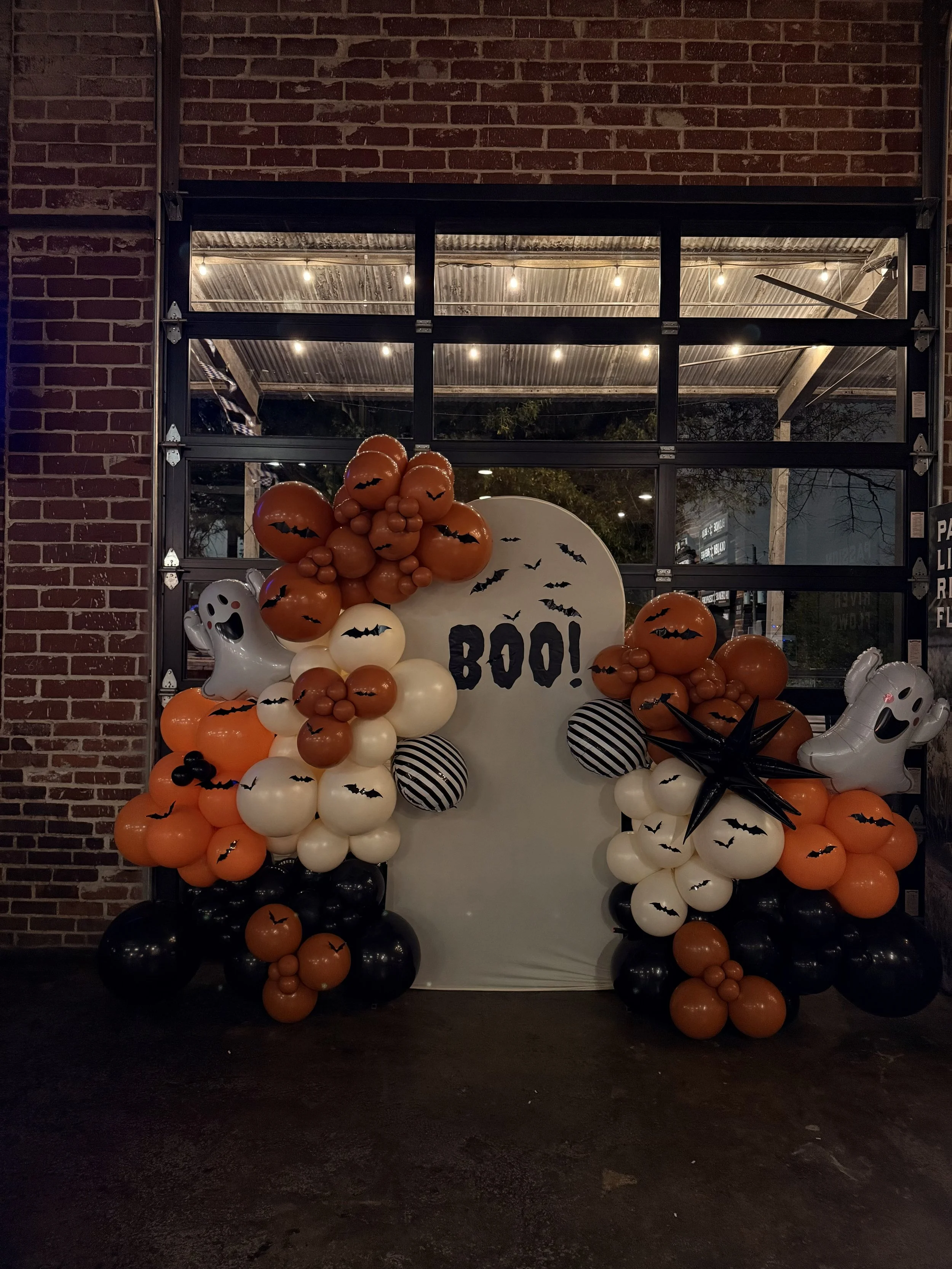 Halloween balloon display with ghosts, bats, pumpkins, and a sign that says 'BOO!'