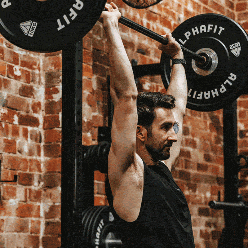 Man lifting a barbell with weights in a gym.