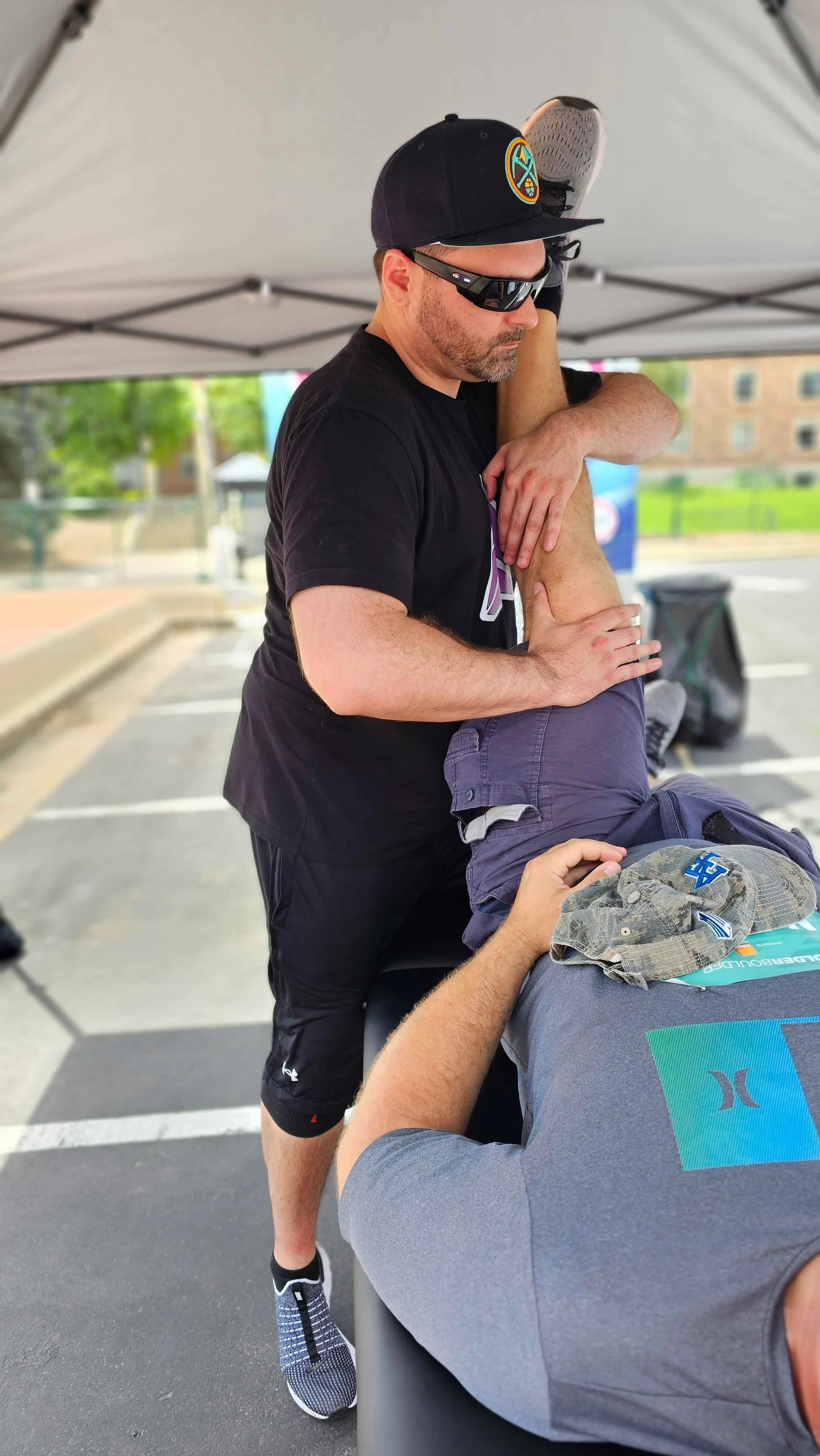 Matt Barcello providing sports massage on a runner’s leg at an outdoor Boulder event – Alleviate Sports Massage
