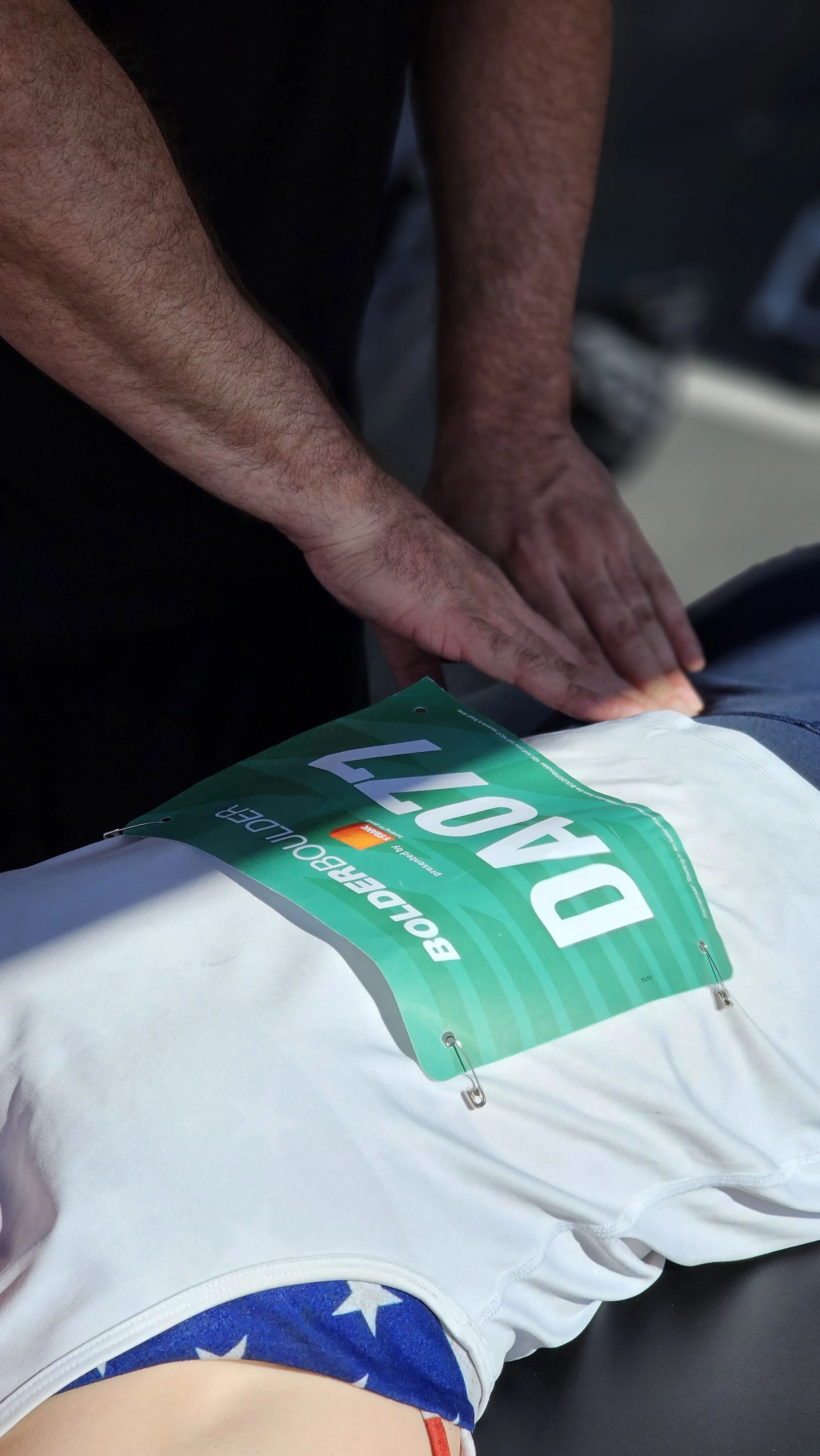 Matt Barcello providing sports massage on a runner’s leg at an outdoor BolderBoulder event – Alleviate Sports Massage