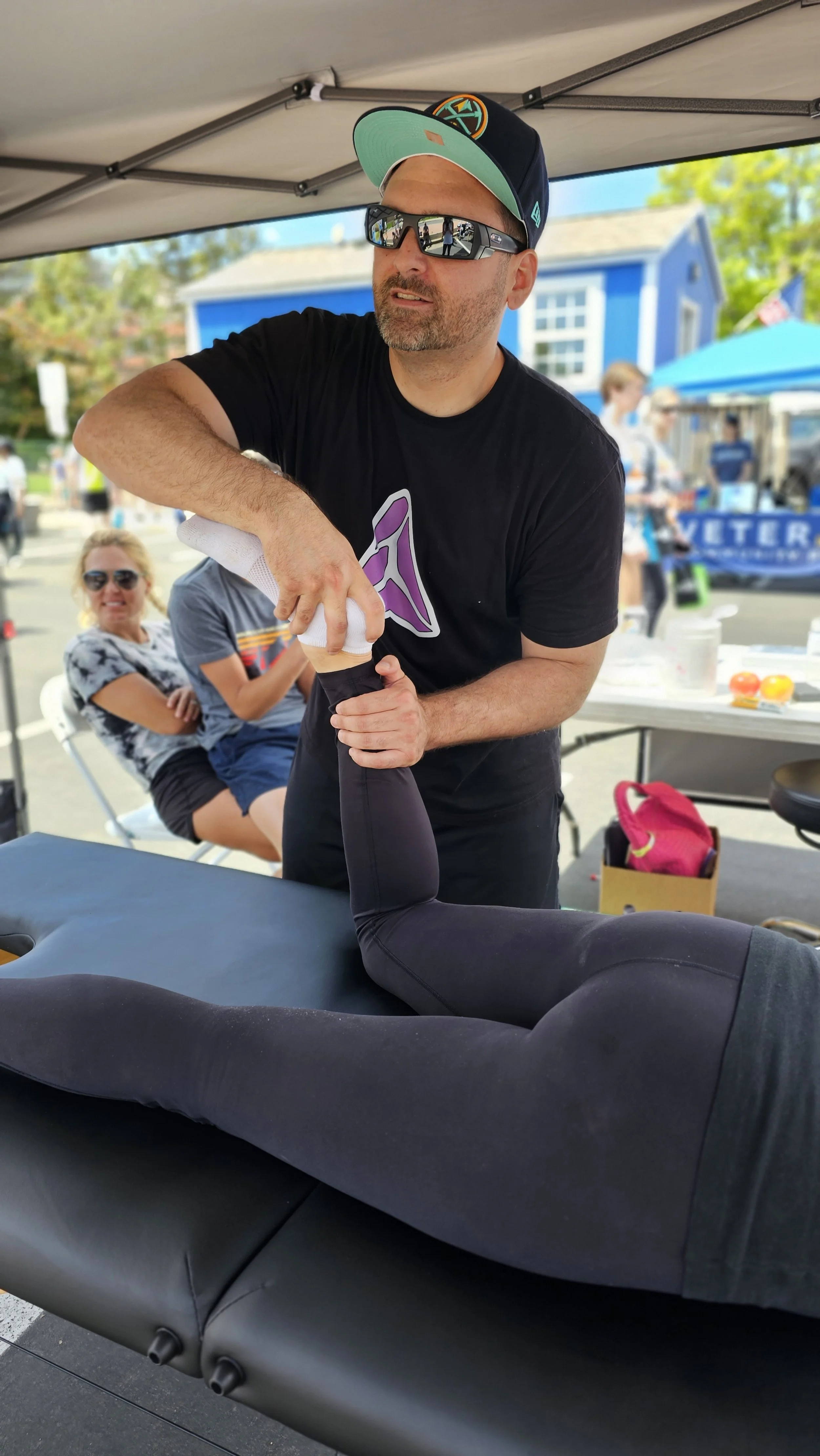 Matt Barcello providing sports massage on a runner’s leg at an outdoor Boulder event called BolderBoulder – Alleviate Sports Massage