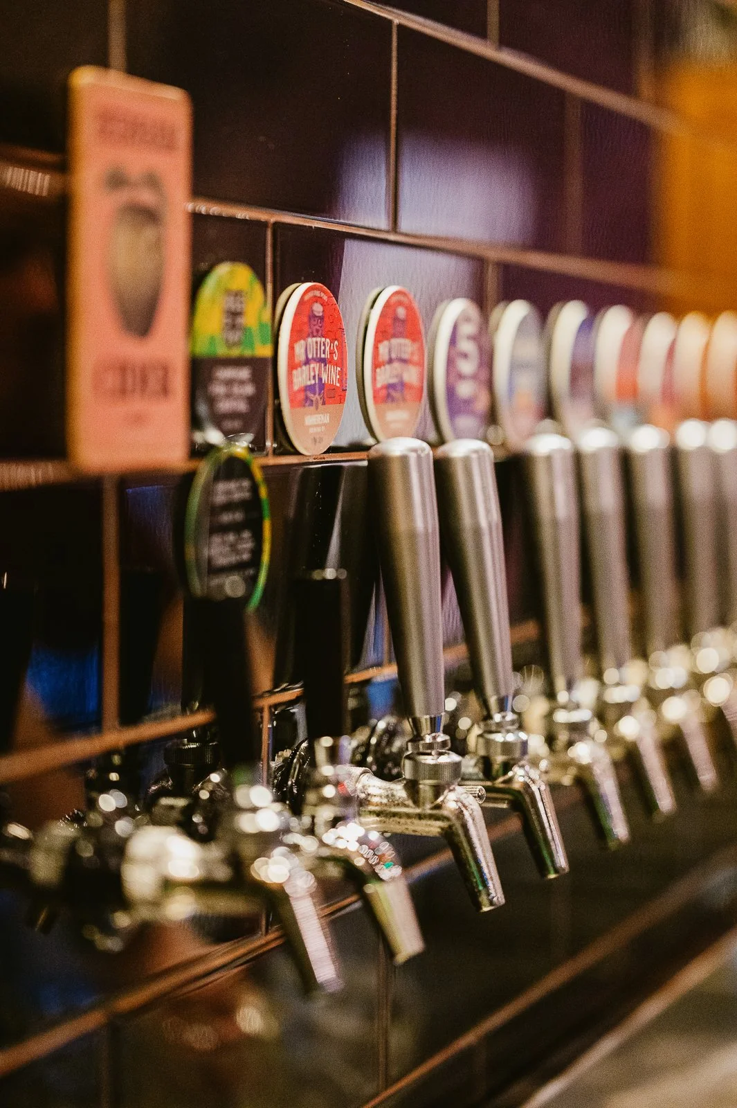 Beer tap handles and pint glass coasters lined up on a bar or brewery countertop.