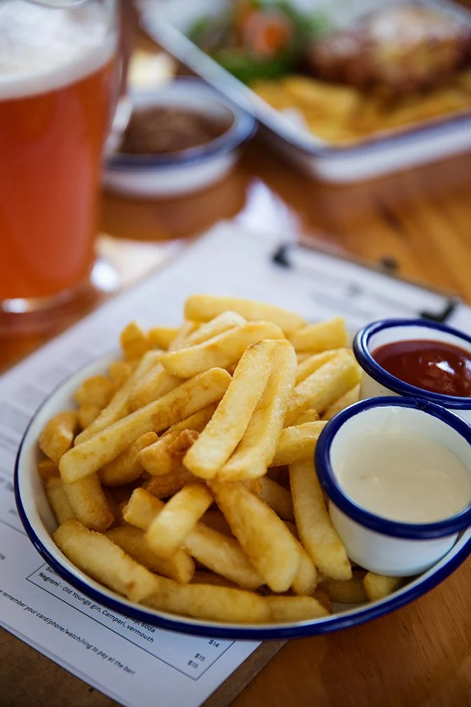 Plate of French fries with ketchup and mayonnaise on a table at a restaurant.
