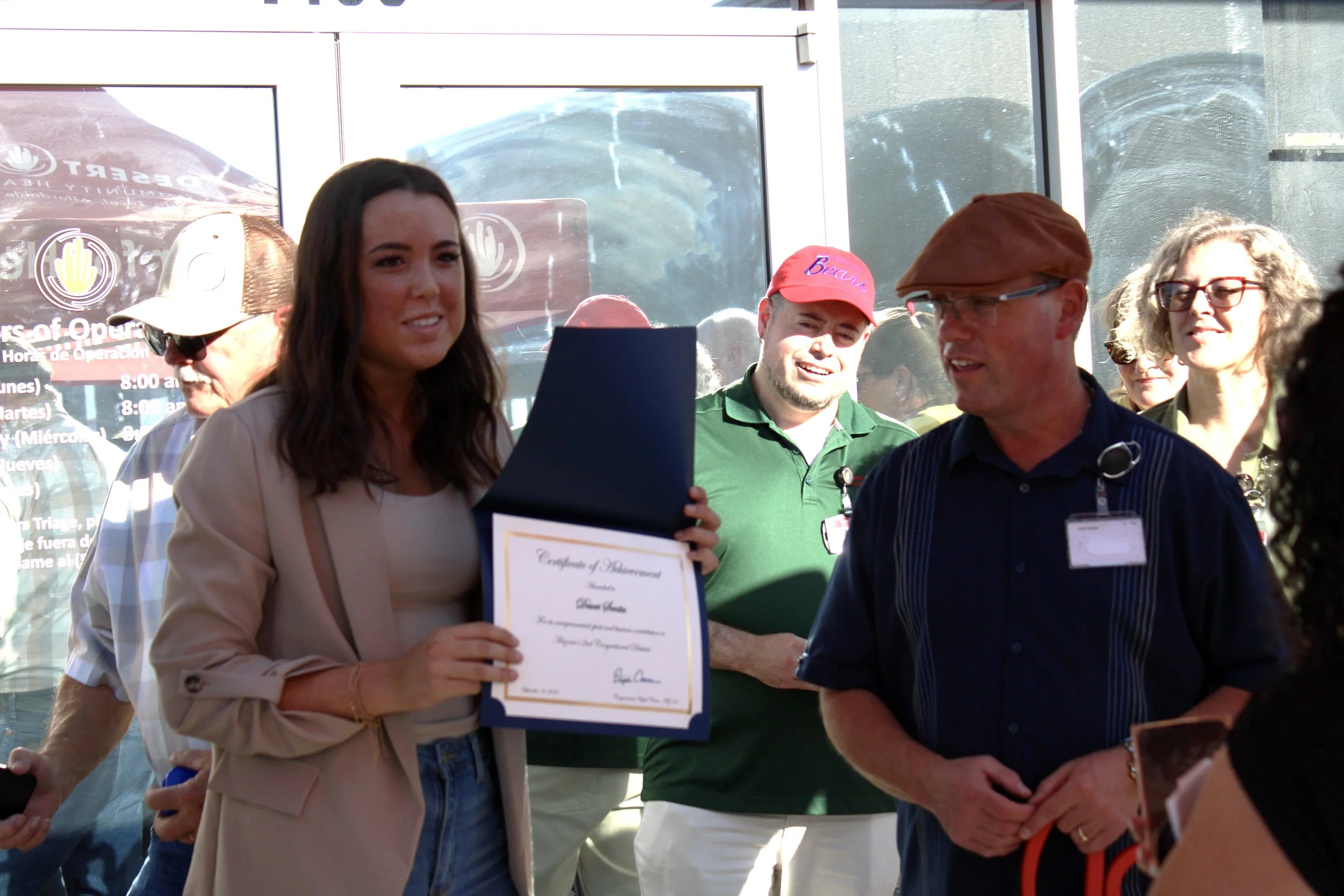 CEO of Desert Senita Community Health Center receiving a Congressional award during the grand opening of Coolidge Clinic, surrounded by people and sunlight. Coolidge, Arizona