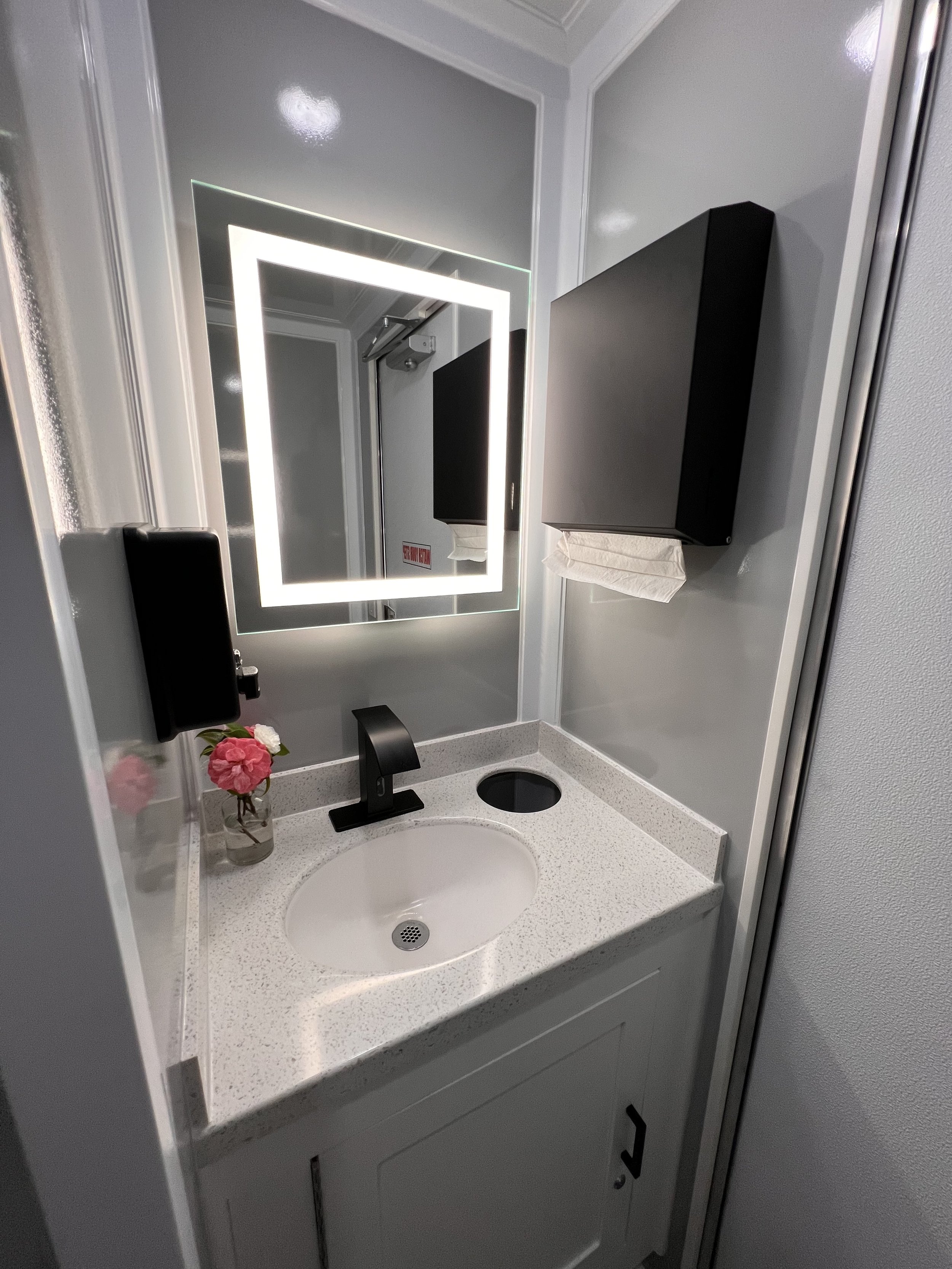 Bathroom with a urinal, a toilet, a gray wall, a gray cabinet with black handles, and a marble countertop.