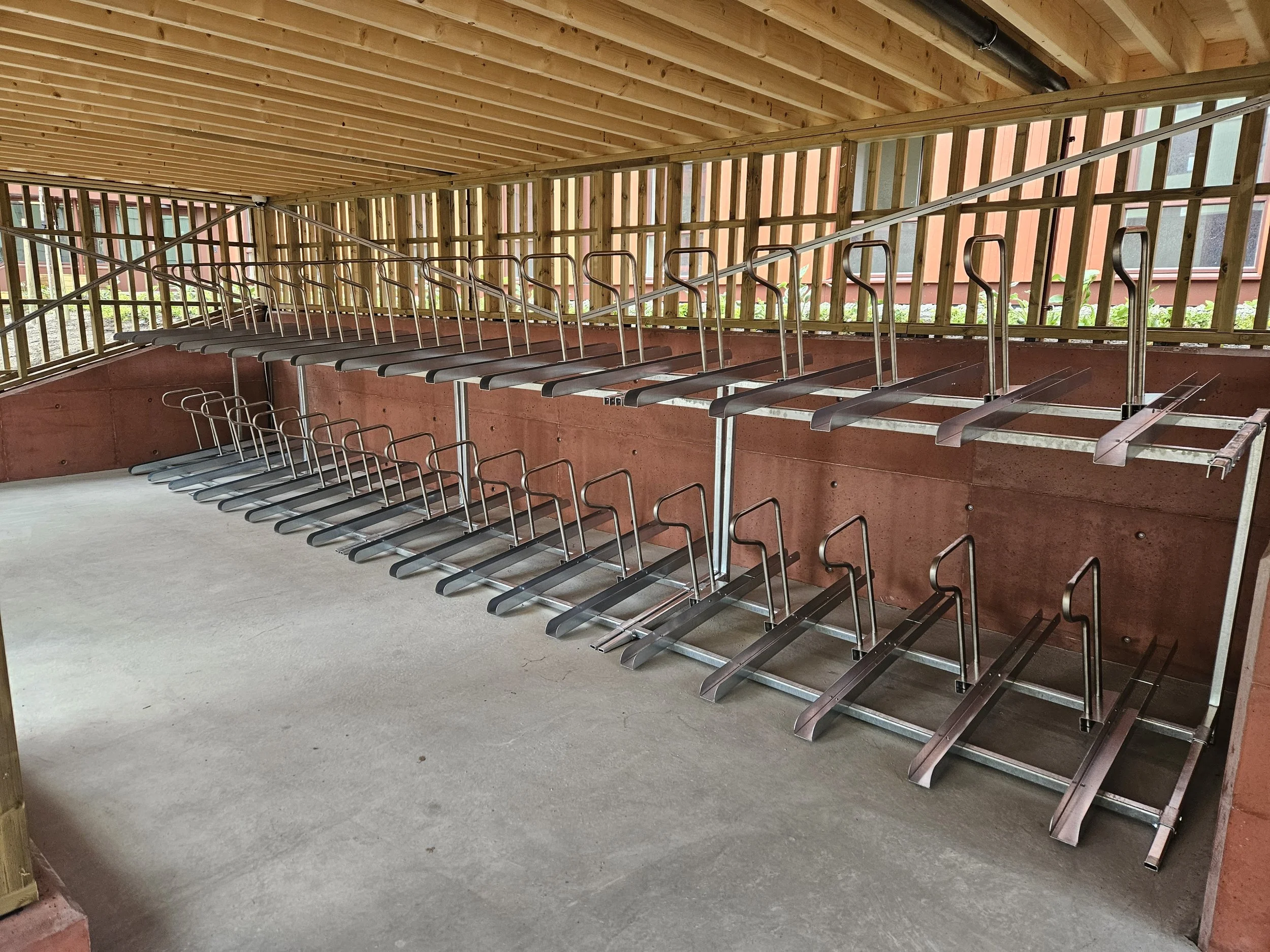 Lagerført sykkelstativ i to etasjer montert i utendørs skur