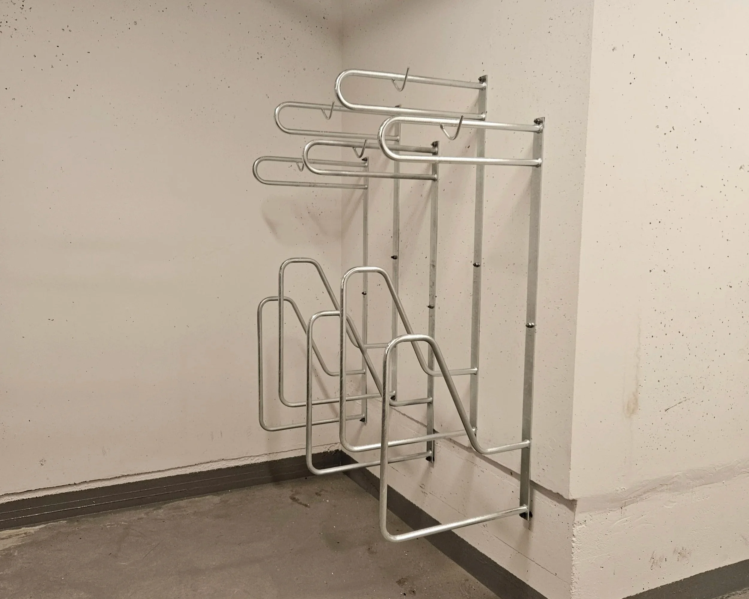 Vegghengt sykkelstativ montert på en betongvegg i en kjeller i et stort borettslag