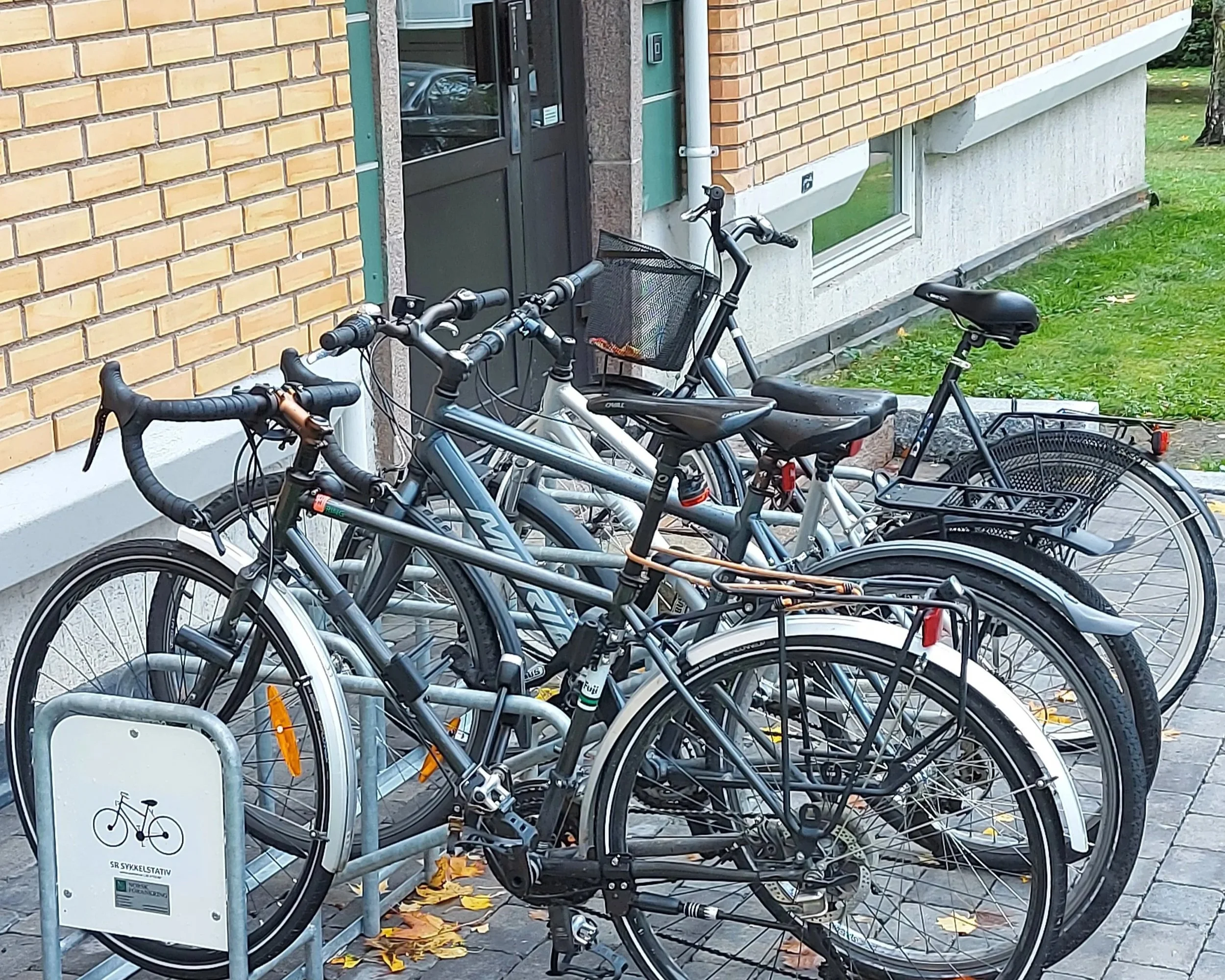 Ensidig sykkelstativ plassert foran inngangsdøren på et borettslag