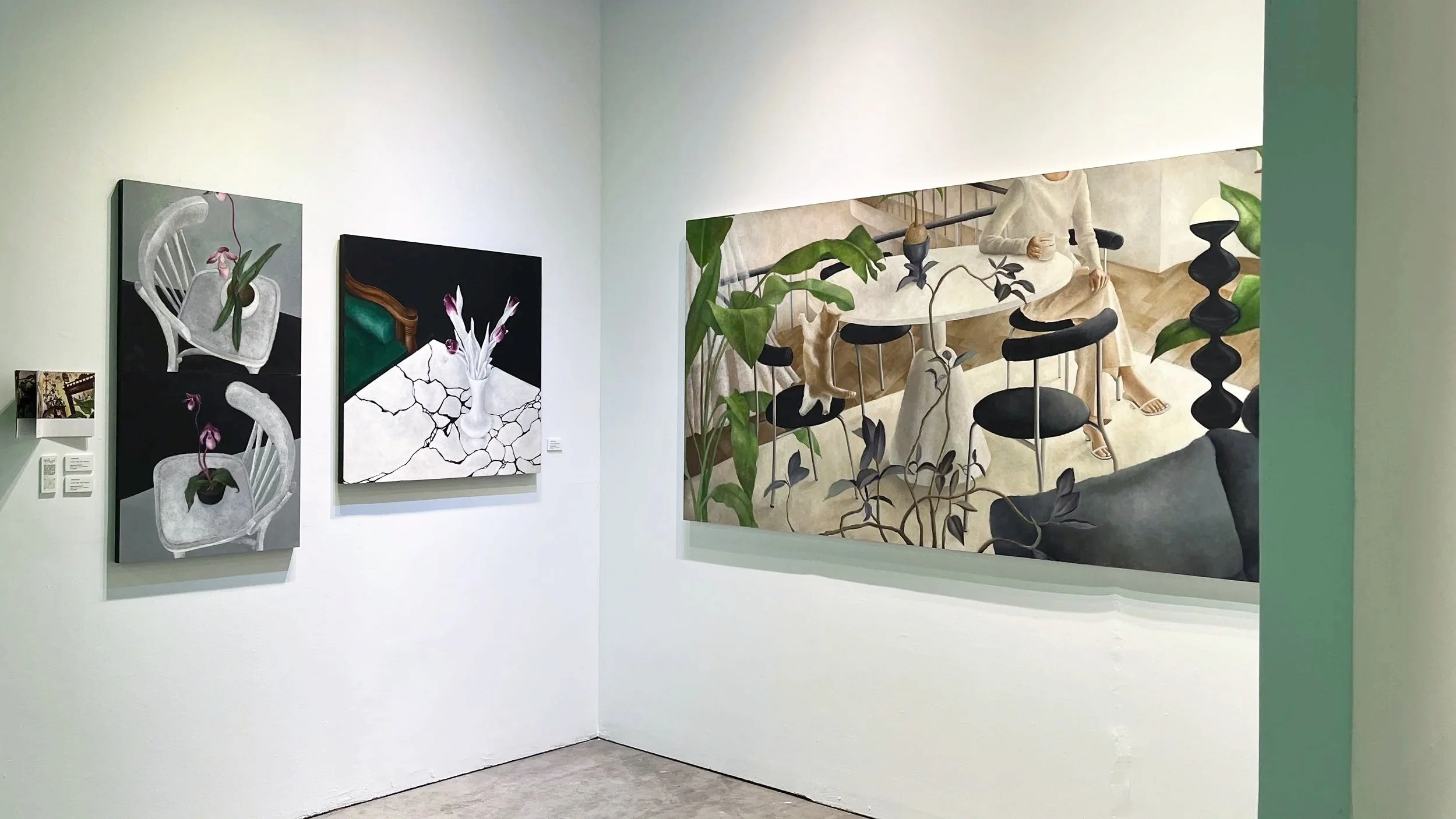 Smart painting wall with four paintings. Two smaller paintings on the left show white chairs with plant pots, and the larger painting on the right depicts a person sitting at a table with chairs and various indoor plants.