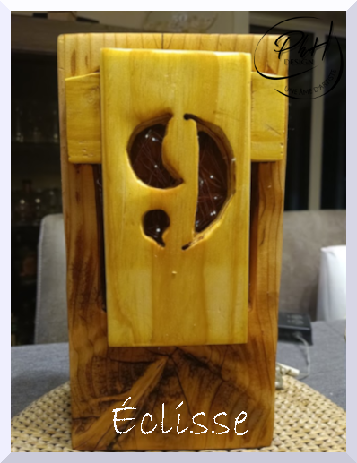 Une décoration en bois gravée représentant une éclipse de lune ou de soleil, avec le mot 'Écluse' écrit en dessous.