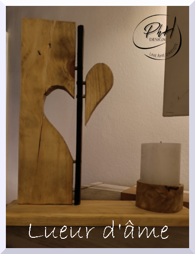 Décoration en bois avec un cœur découpé, une bougie blanche sur un support en bois, et un logo artistique en haut à droite. Texte 'Lueur d'âme' en bas.