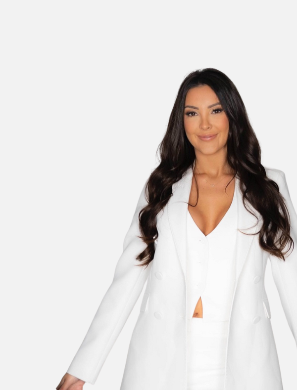 A woman with long dark hair wearing a white suit and blouse, smiling against a plain white background.