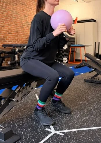 Female athlete performing goblet squats in sports rehab performance clinic