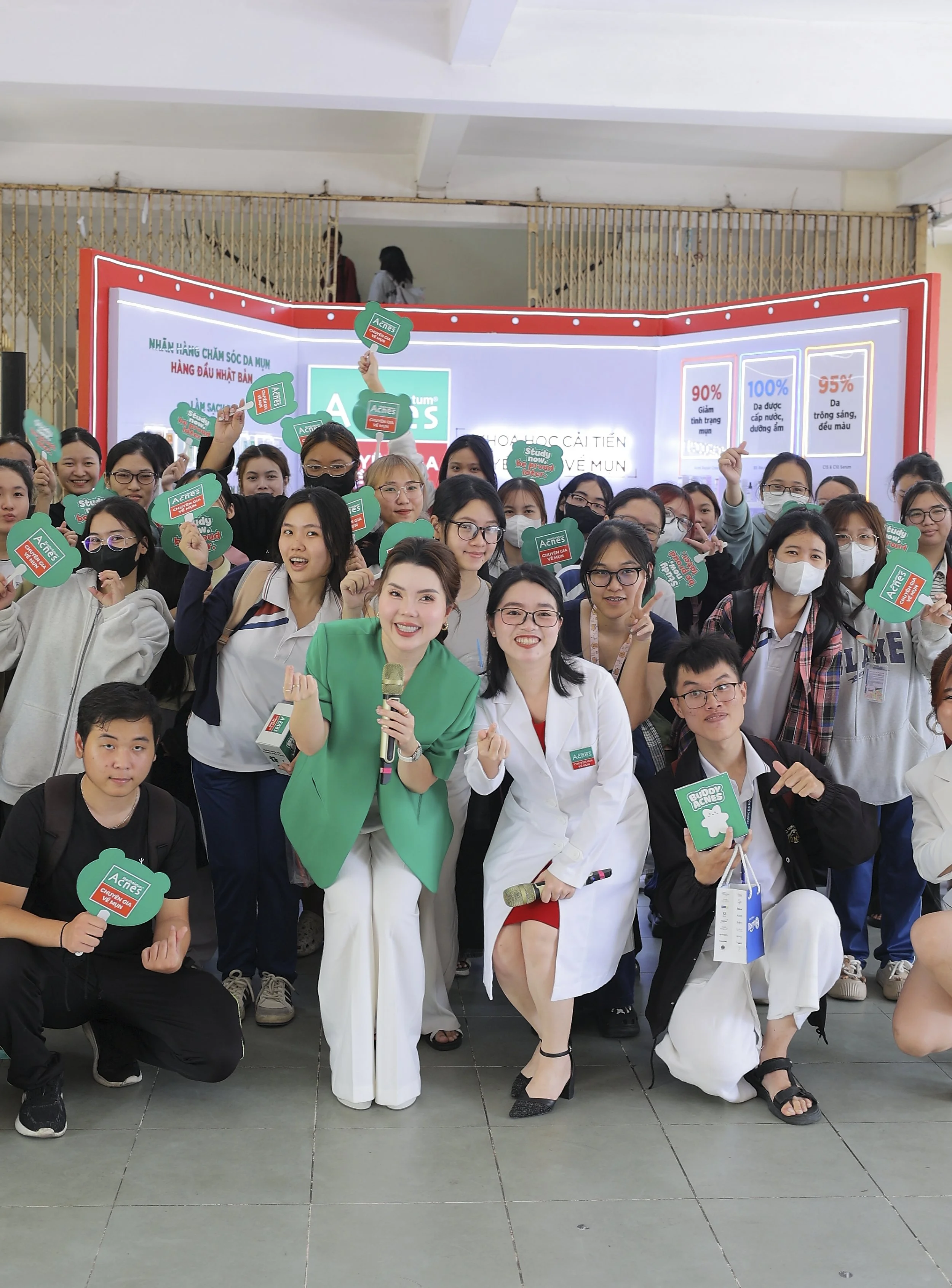 Group of people at an event holding green and red advertising signs, some wearing masks, posing for the photo.