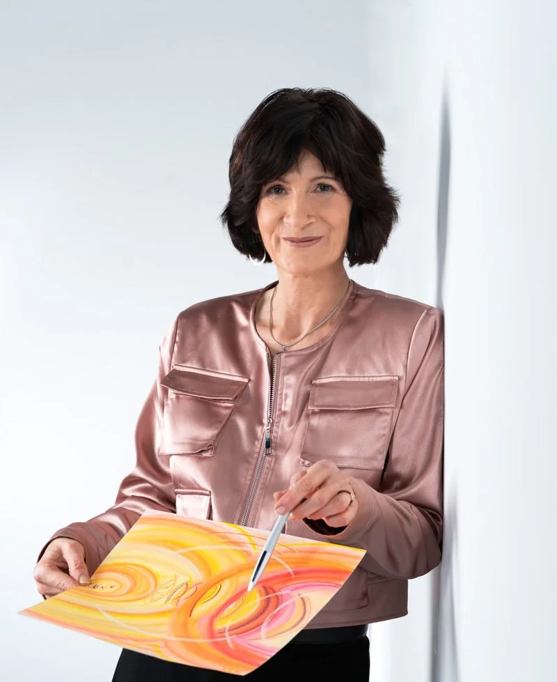 Eine Frau mit dunklem, lockigem Haar hält einen bunten, abstrakten Gemälde mit einem Stylus in der Hand.