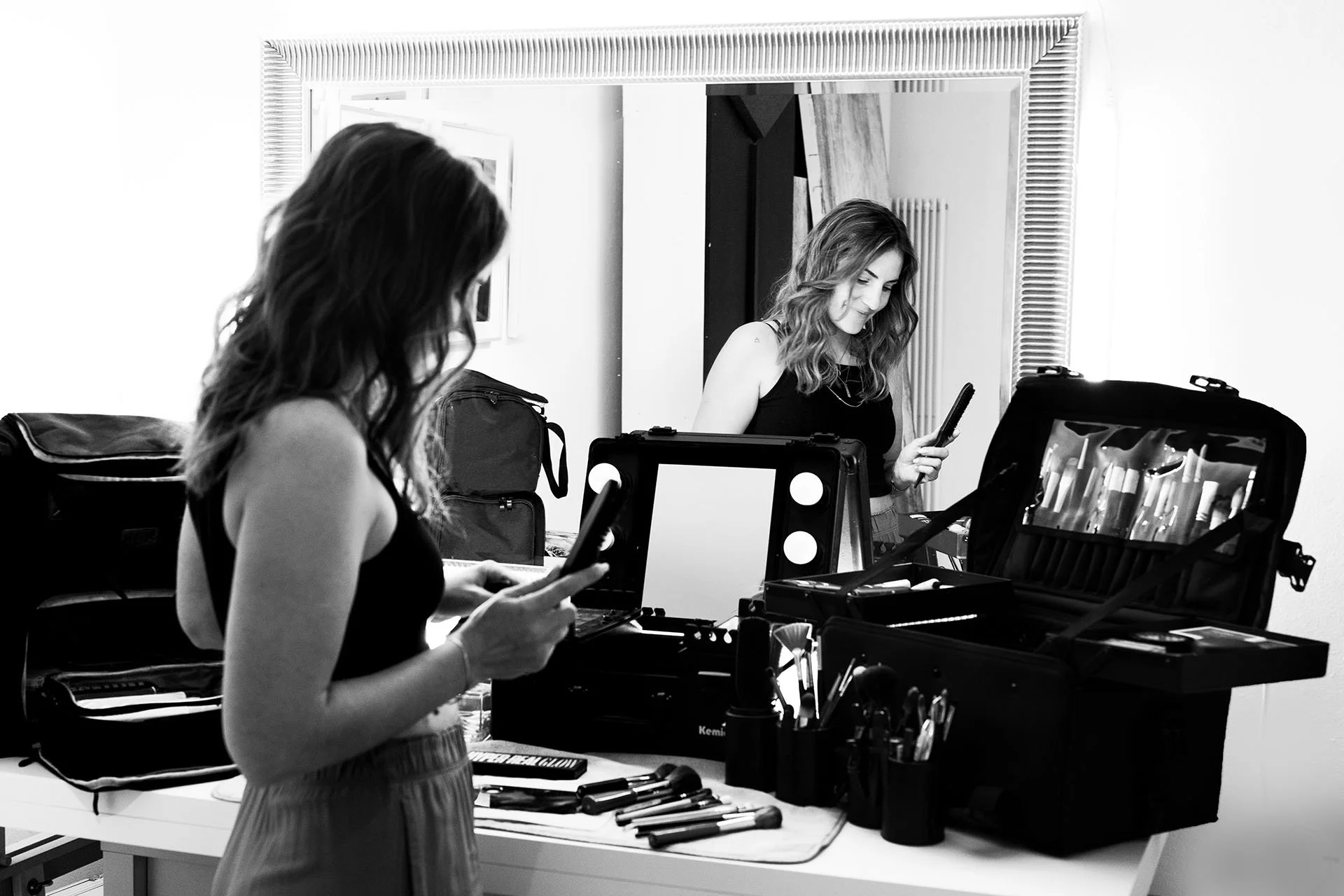 Zwei Frauen bereiten Make-up für ein Fotoshooting vor, mit Make-up-Tools und Spiegel in einem Raum.