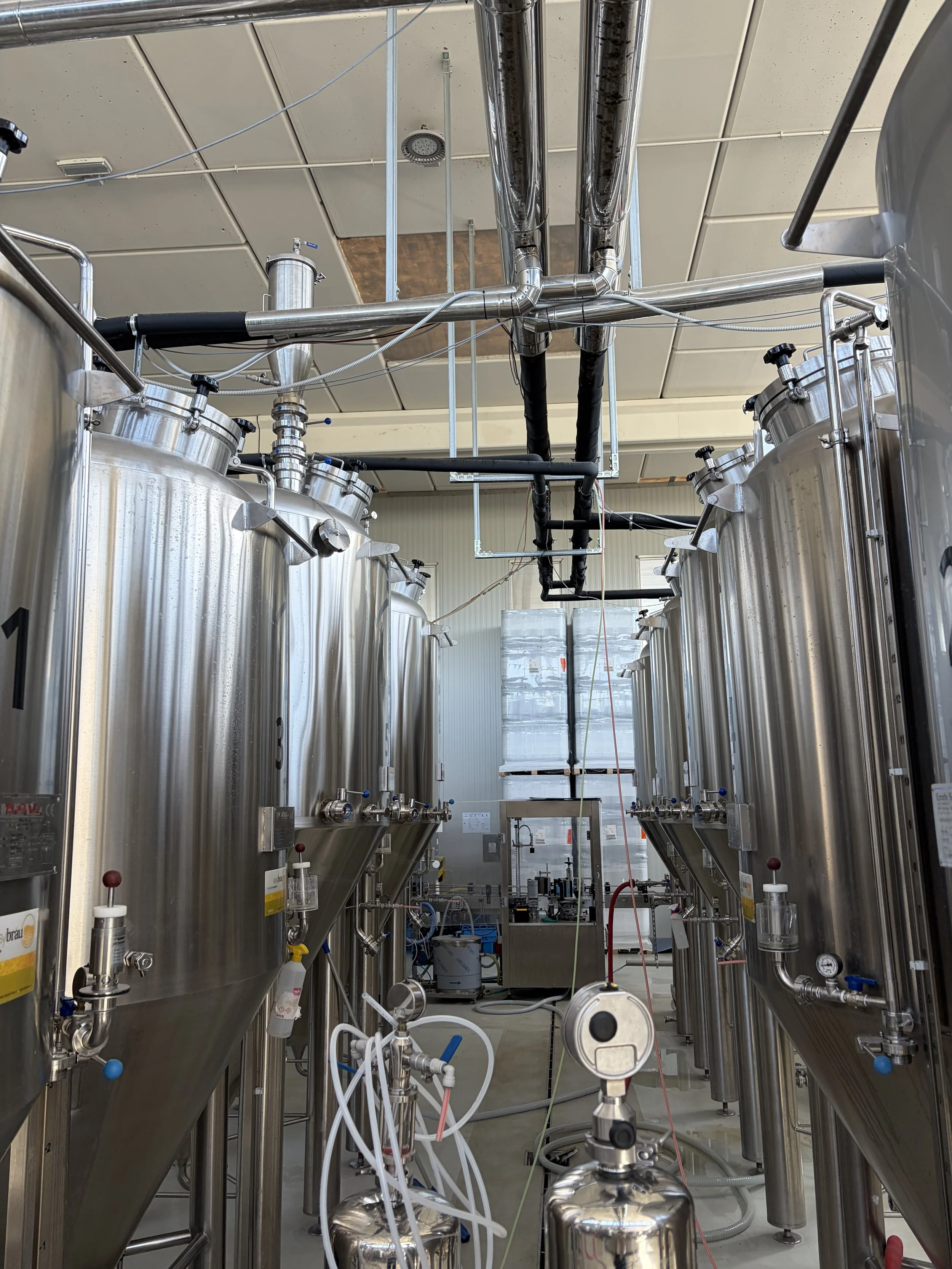 Industrial or laboratory equipment with large stainless steel tanks, pipes, and various control valves, possibly used for manufacturing or scientific processes.