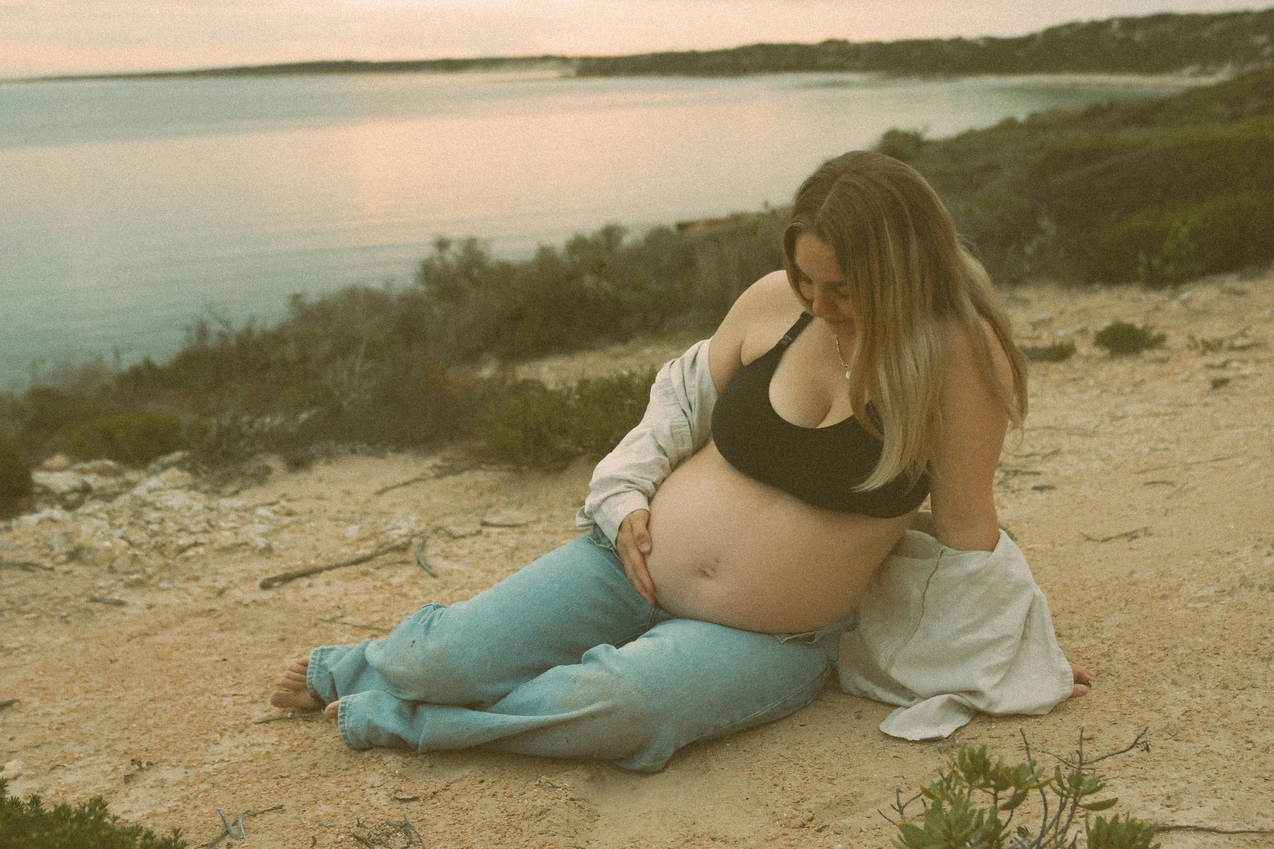 mother sitting on sand dune during maternity photoshoot in ceduna