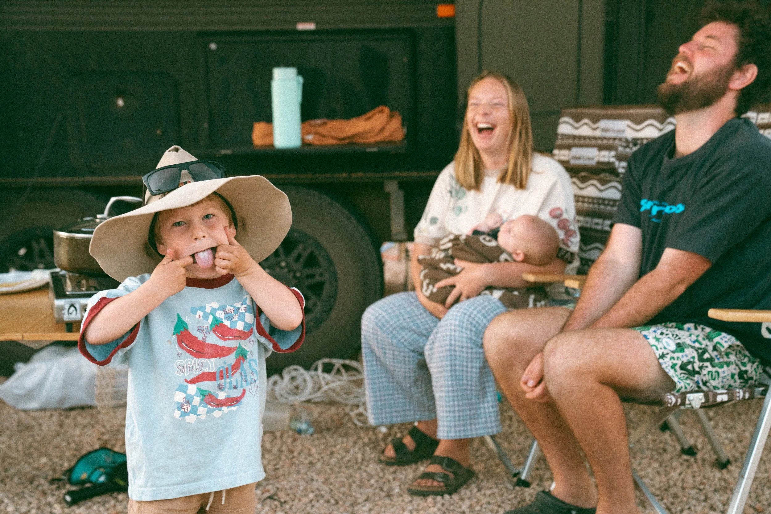 mum holding a baby dad laughing while toddler pulls faces at the camera during a caravan family photoshoot at ceduna bug 4 caravan park