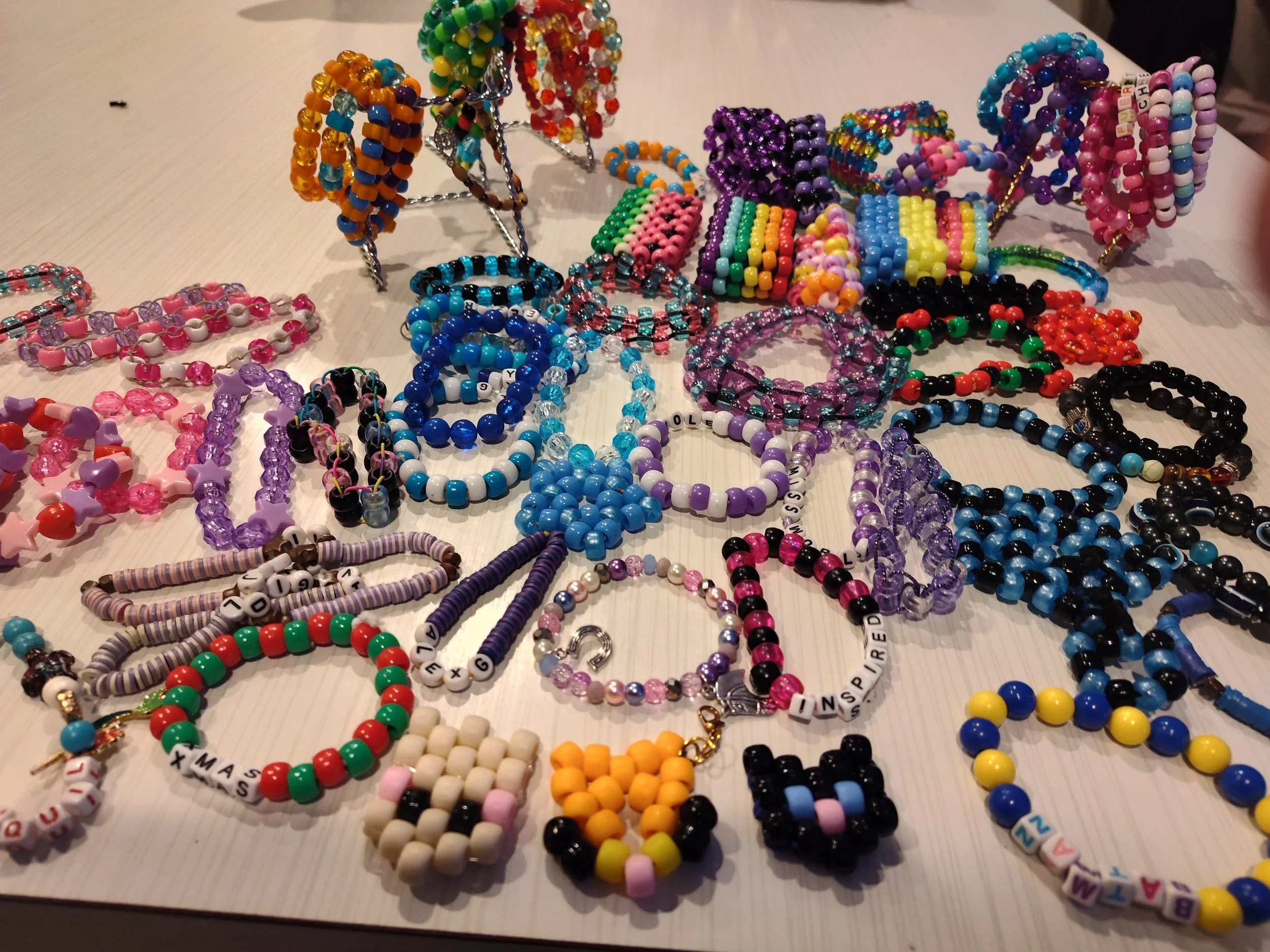 Colorful beaded jewelry including bracelets and necklaces arranged on a white table.