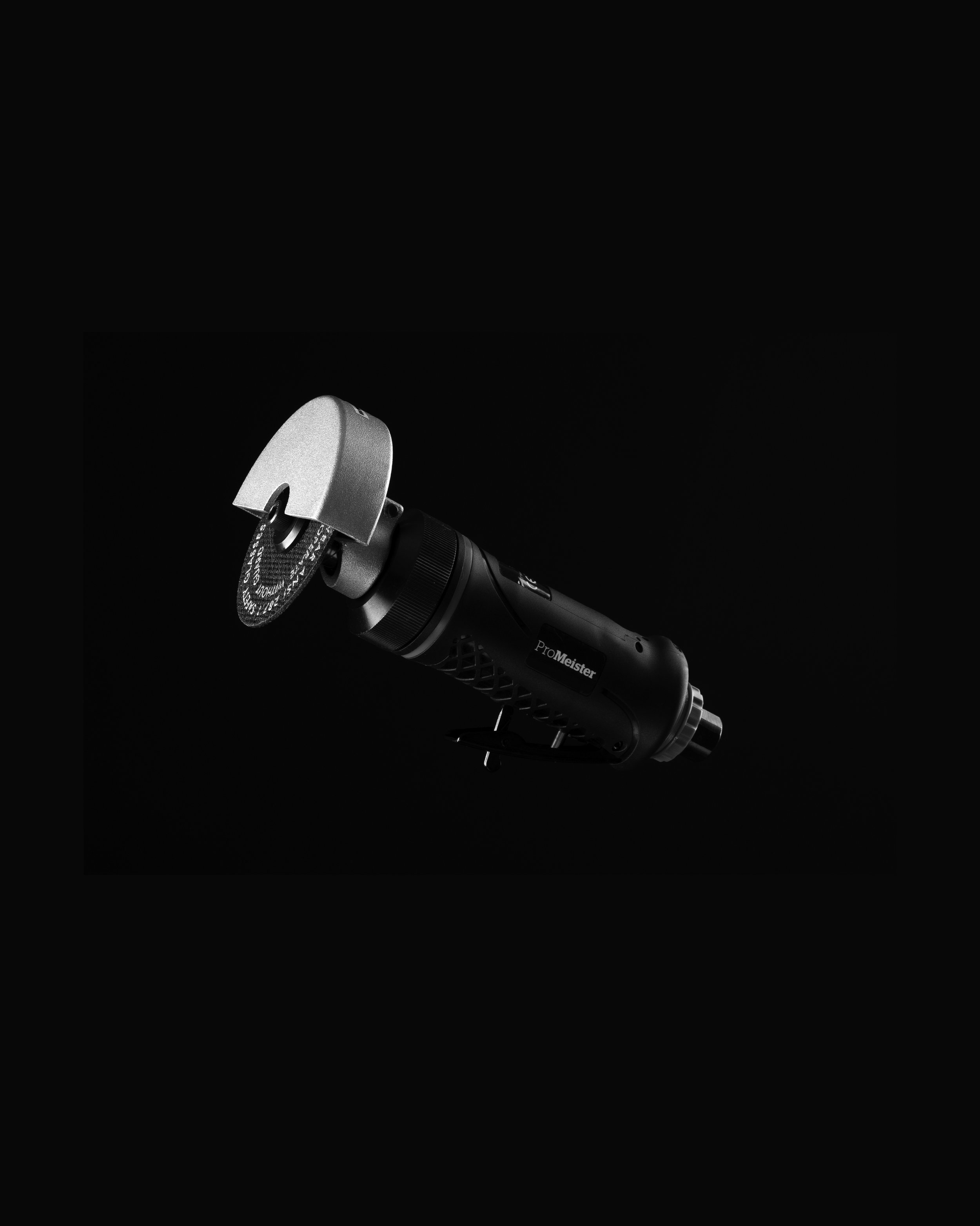 A black and silver electric rotary tool with a circular cutting disc attached, isolated against a black background.