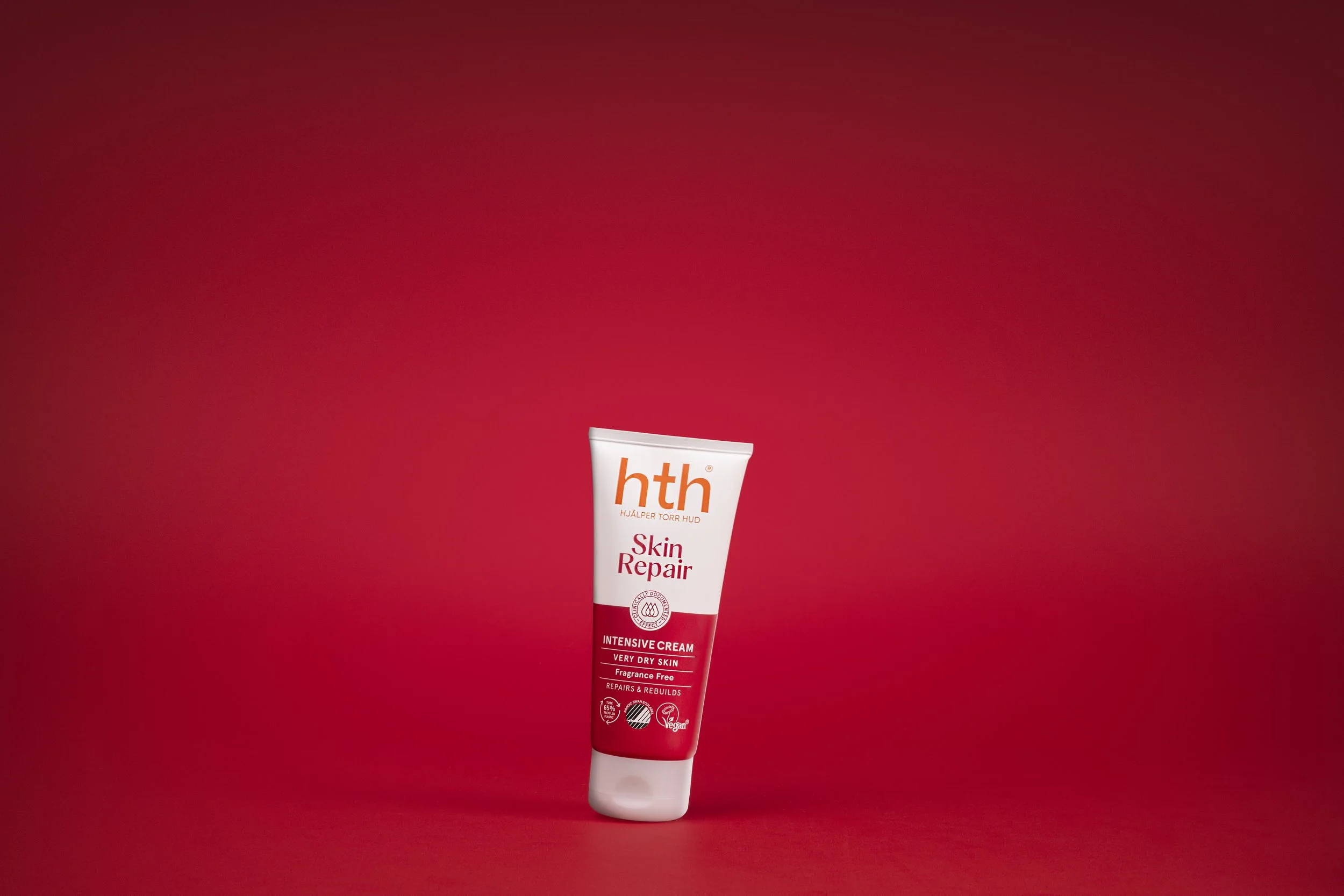 A tube of HTH Skin Repair Intensive Cream for very dry skin against a red background.