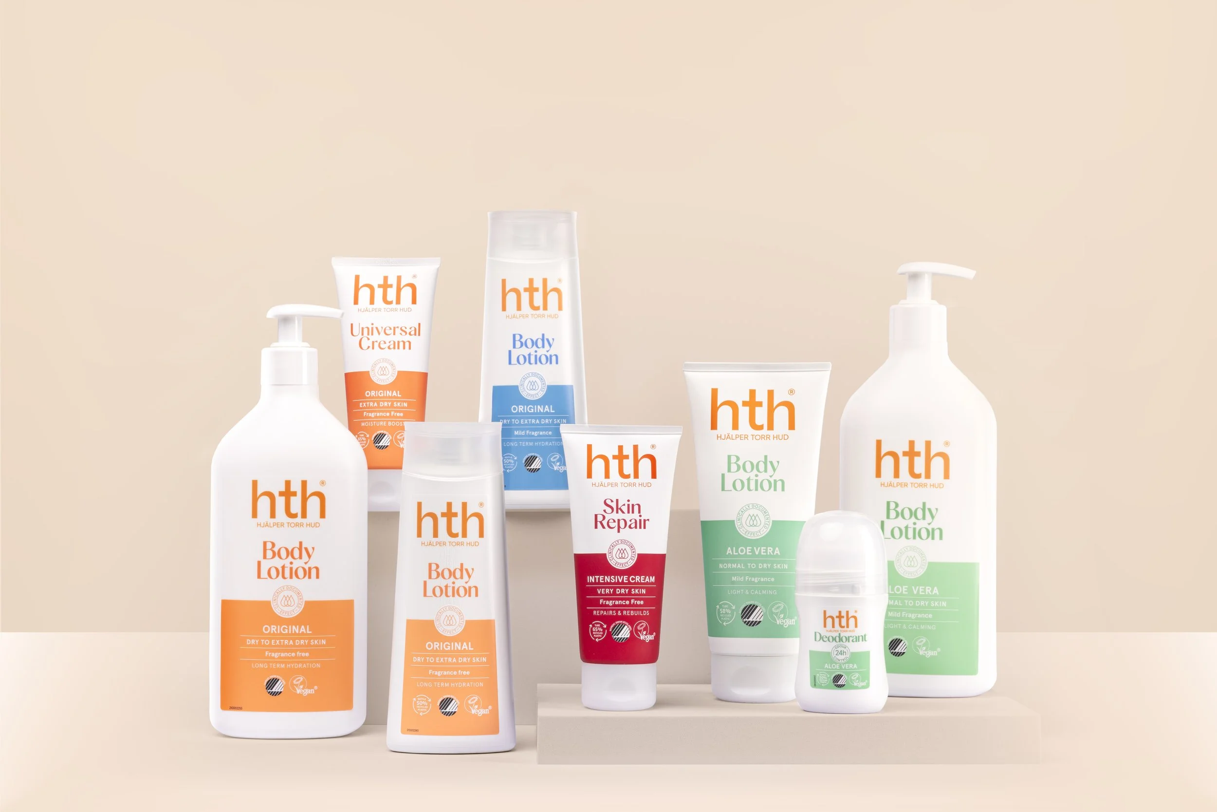 Nine bottles of personal care products from the hth brand, including body lotion, universal cream, body lotion, skin repair cream, aloe vera body lotion, deodorant, and others, arranged on a beige platform against a beige background.