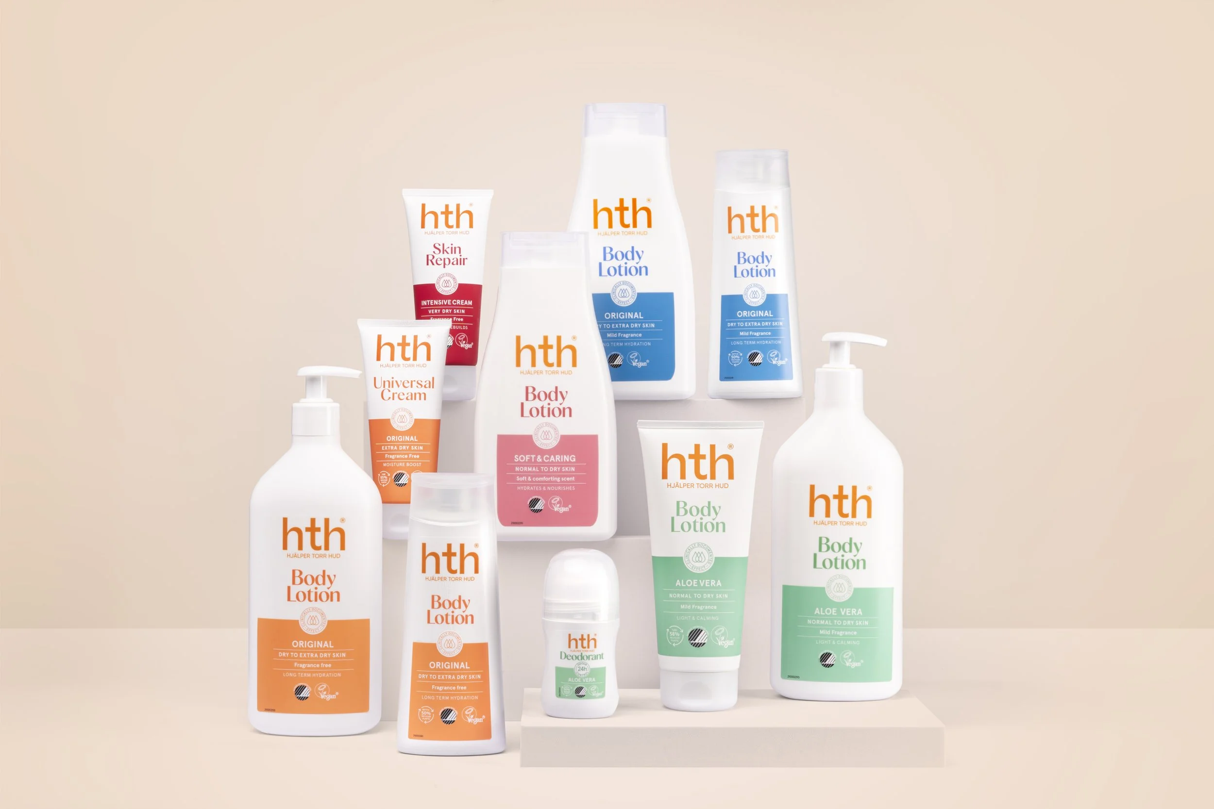 Collection of skincare and body lotion products from the brand hth, including various bottles, tubes, and containers with labels in orange, pink, green, and blue, displayed on a beige surface against a light background.