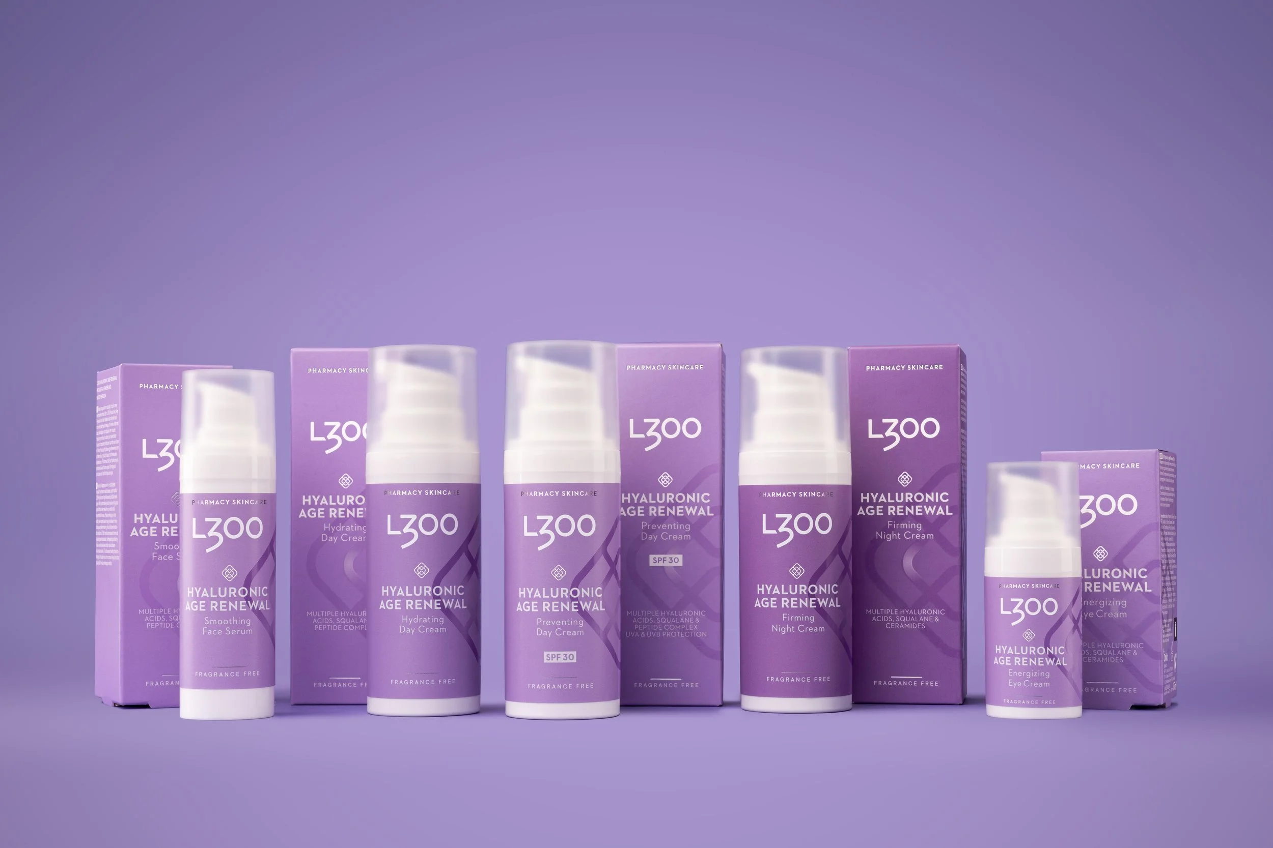 Several bottles and boxes of L300 Hyaluronic Age Renewal skincare products in purple packaging on a purple background.