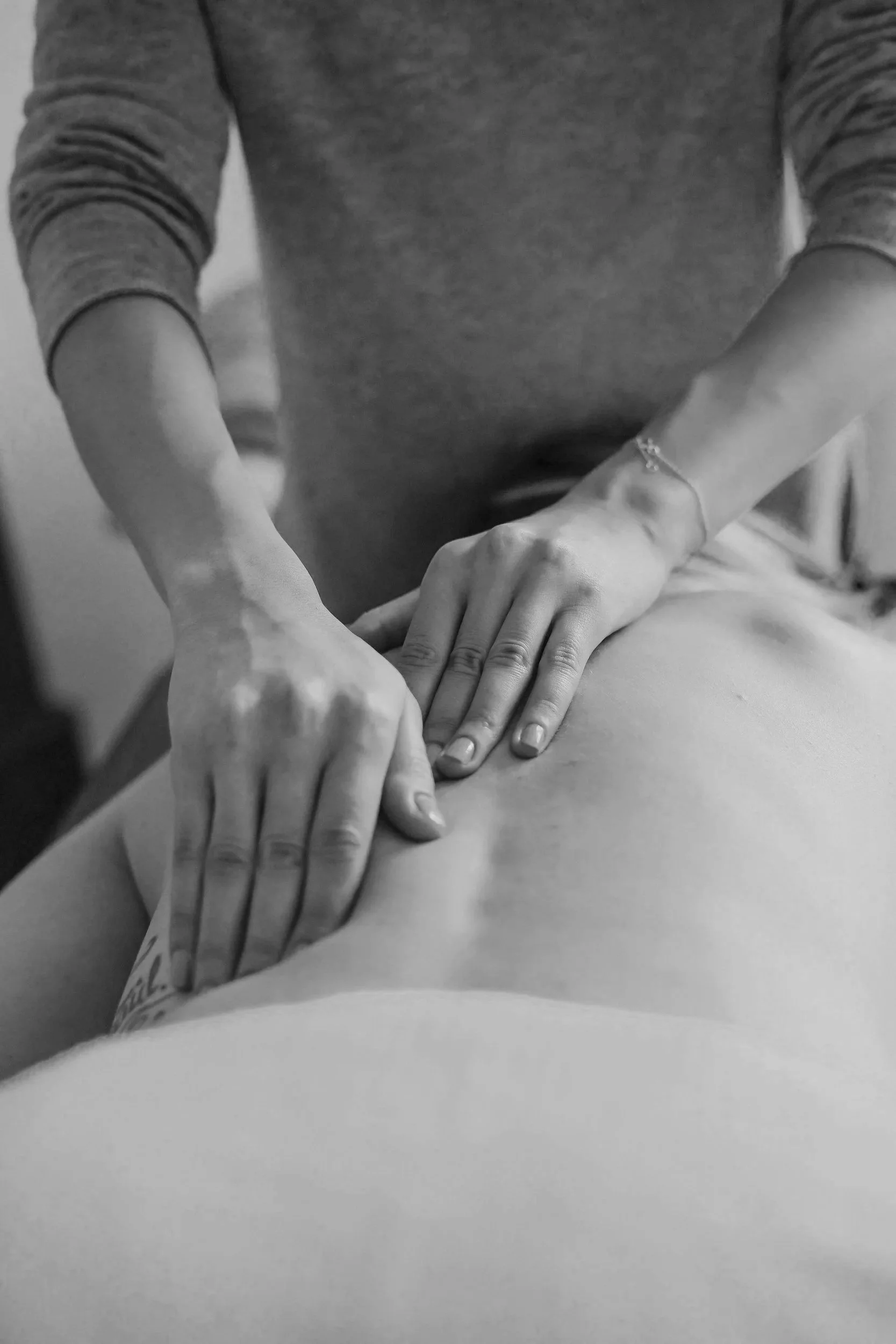A person giving a massage to someone lying face down, focusing on their back.