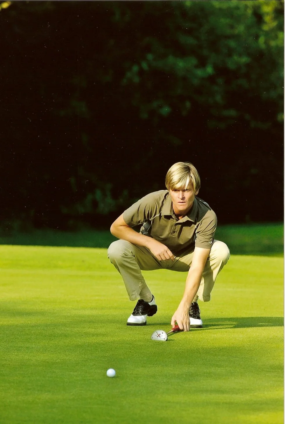 Man die een golfbal op de green plaatst en klaar is om te slaan.