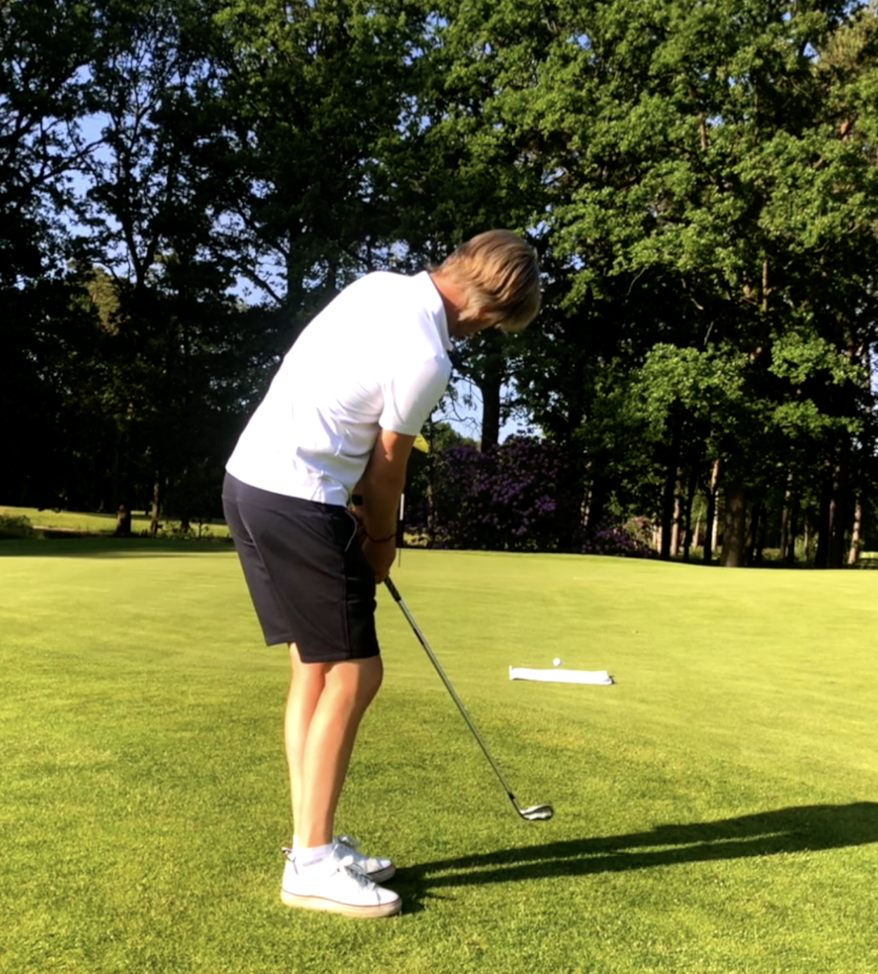 Persoon die een golfbal op een golfbaan slaat.