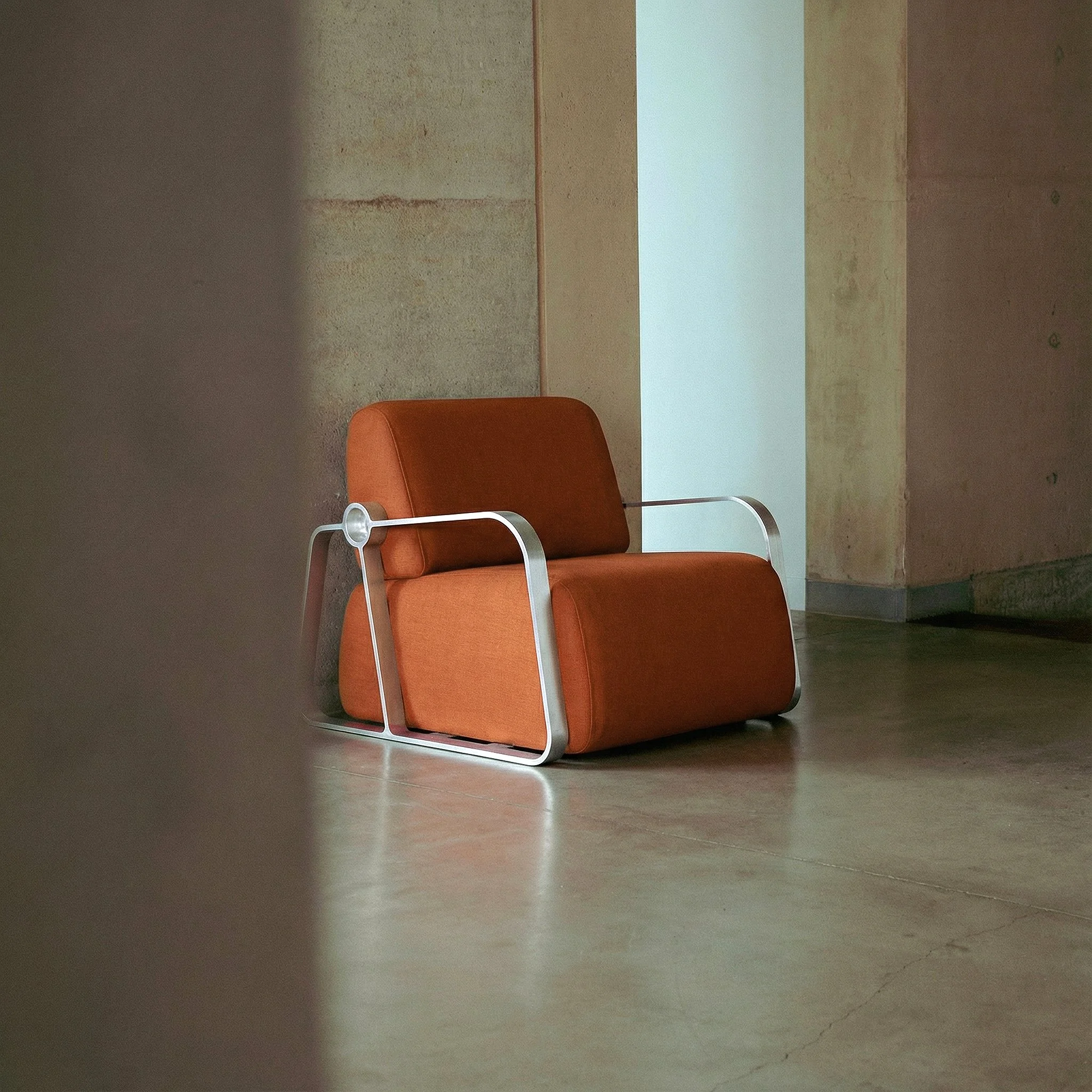 Putney Chair by New Zealand designer Andrew Roberts — a contemporary lounge chair combining soft moulded foam upholstery with a cast aluminium frame and armrests, designed for comfort, durability, and modern interior spaces.