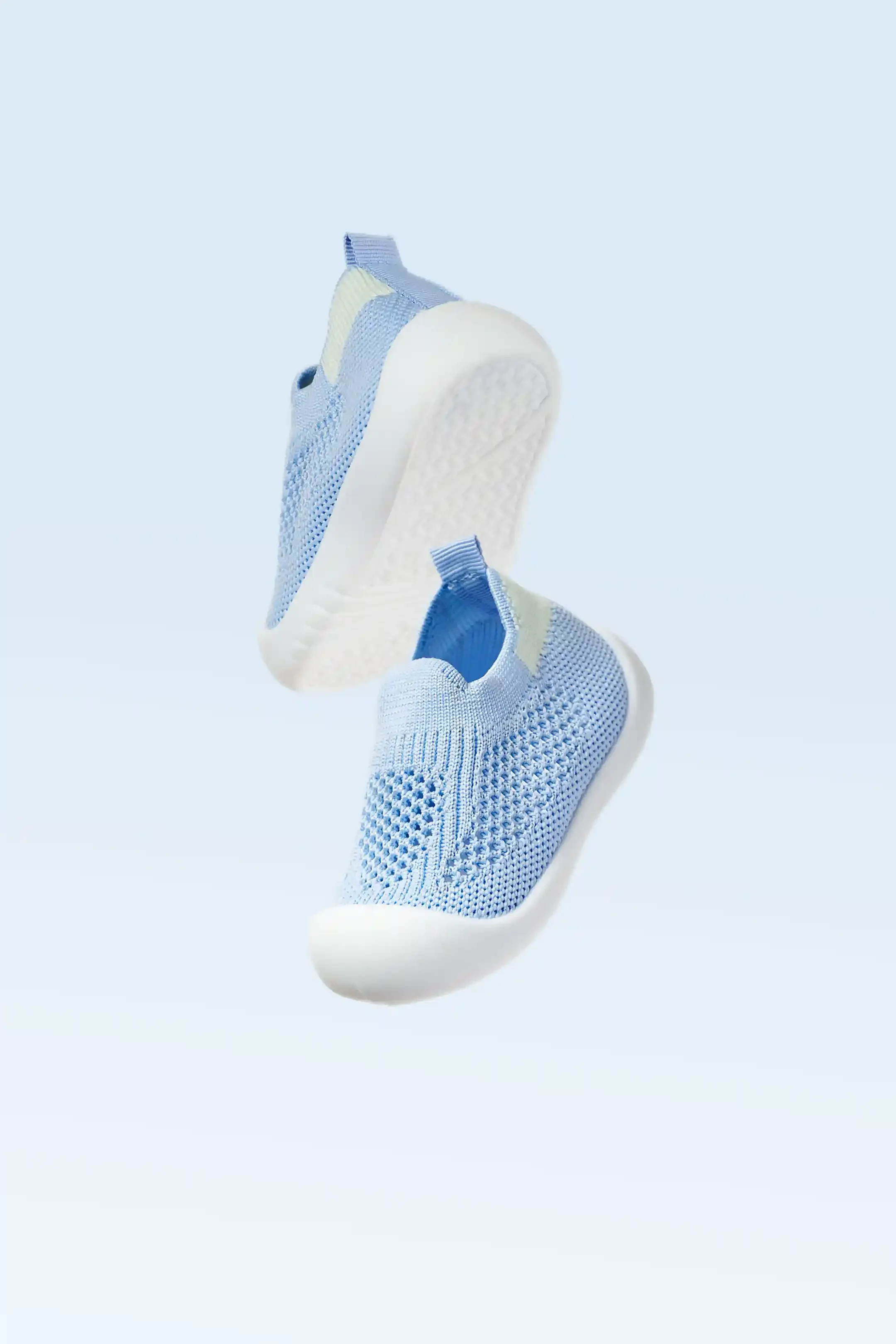 Une paire de baskets légères de couleur bleue et blanche flottant sur un fond bleu clair.