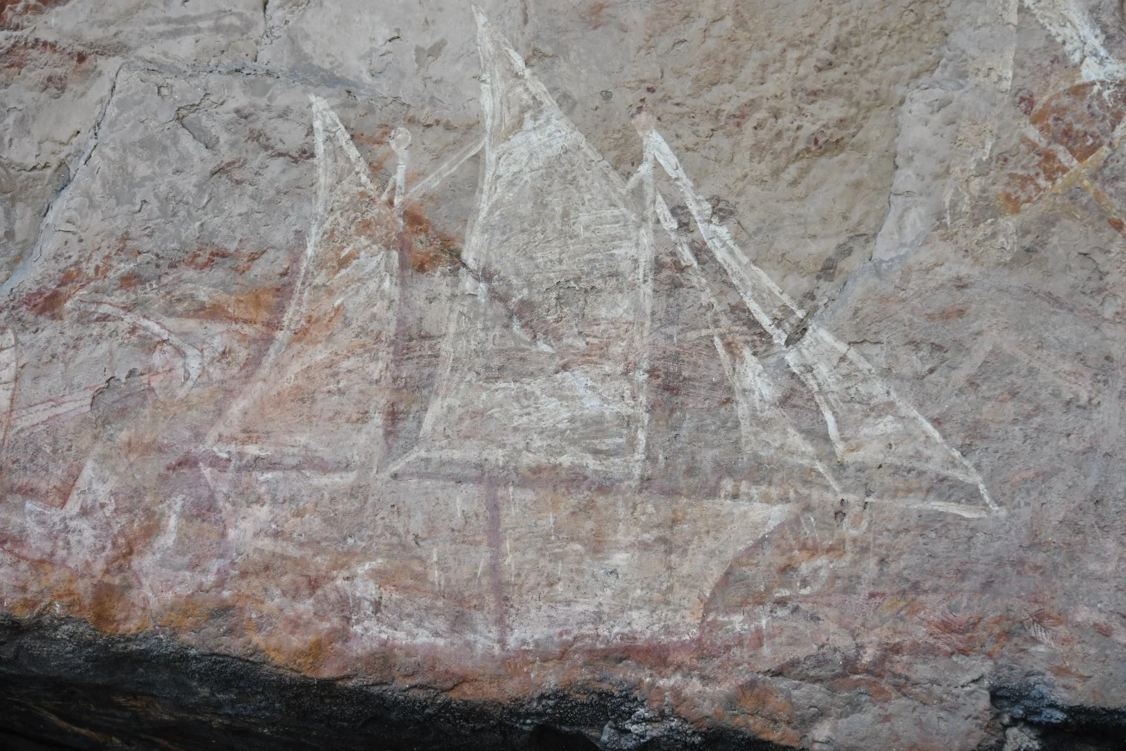 Prehistoric cave painting of abstract geometric shapes and figures on a rough stone wall.
