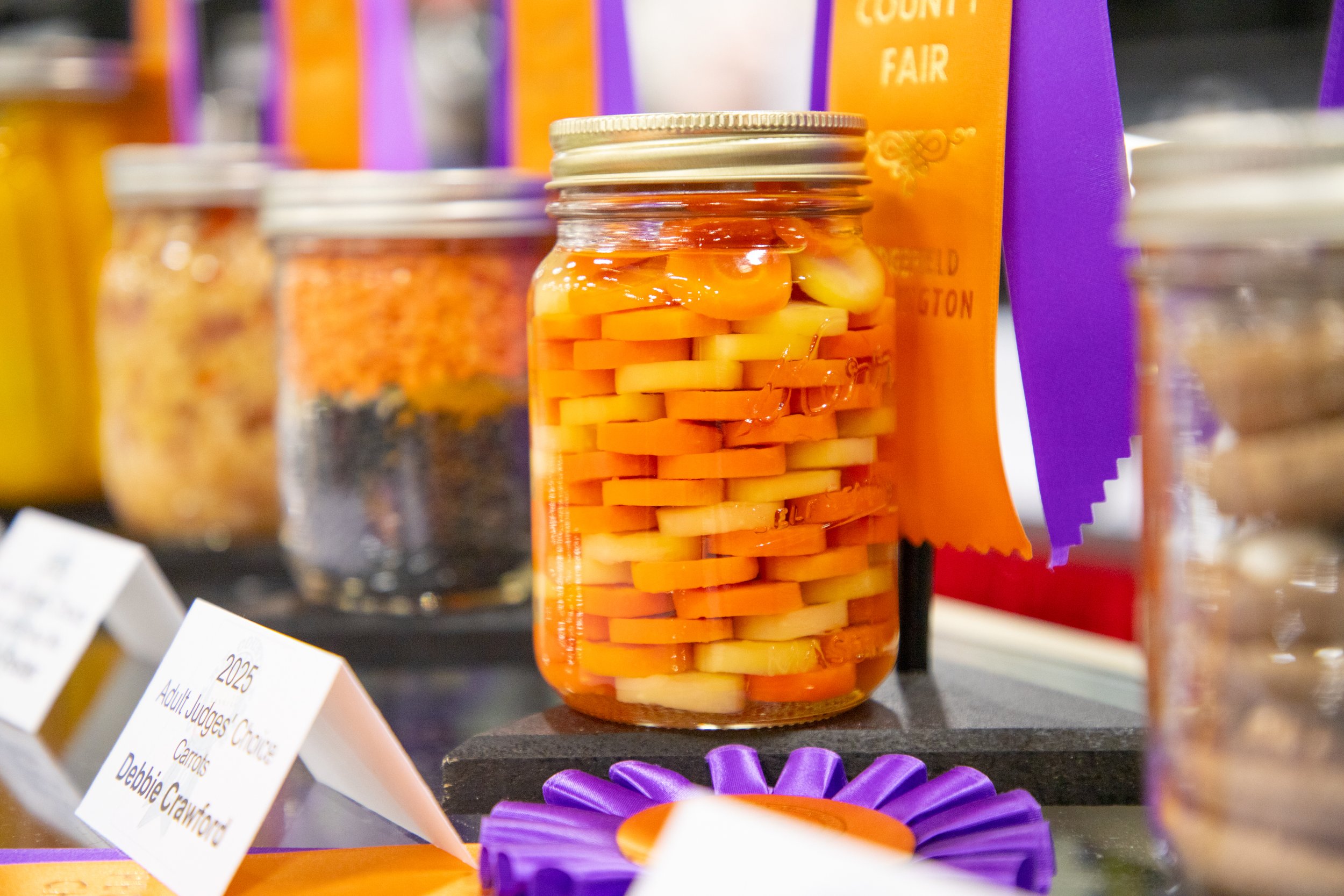 Canned veggies layered in a glass jar with rosette award ribbons