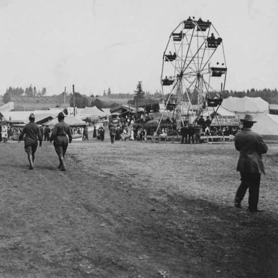 A photo from the early days of the Clark County Fair showing people walking in front of rides and booths
