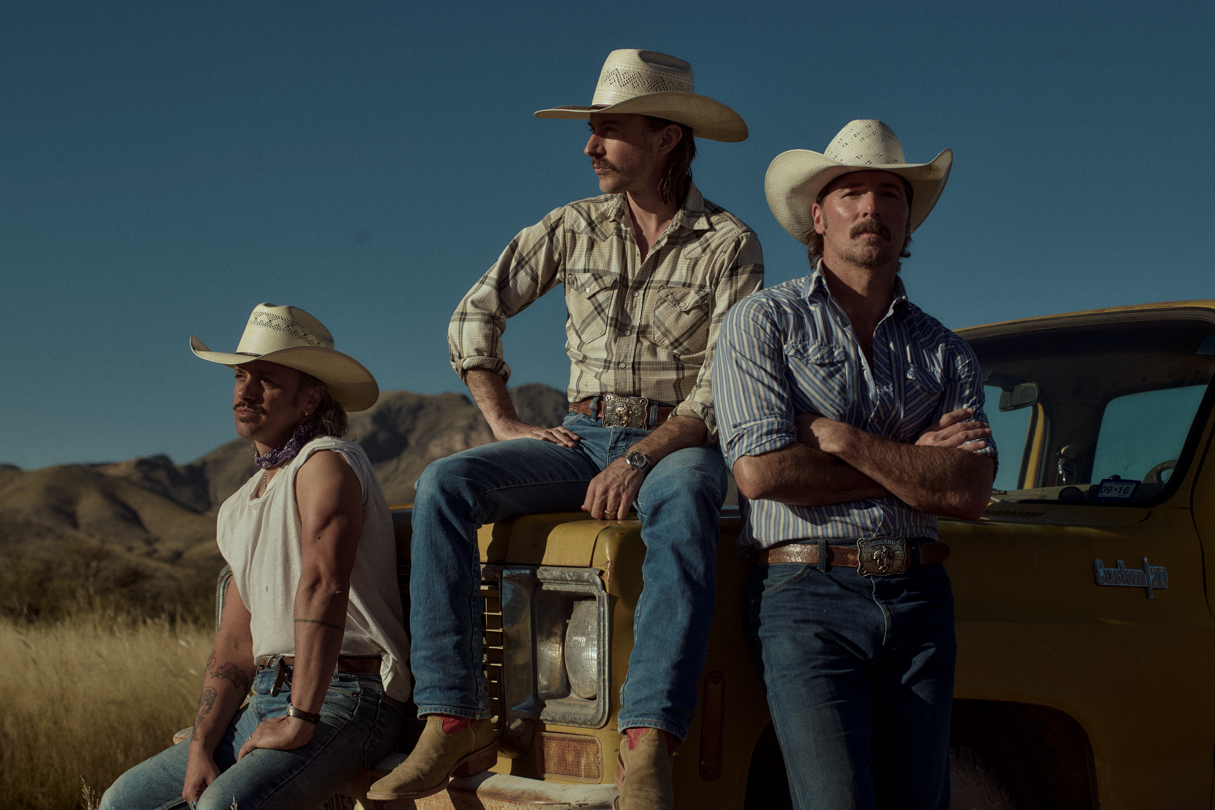 Members of the band Midland sitting on a truck