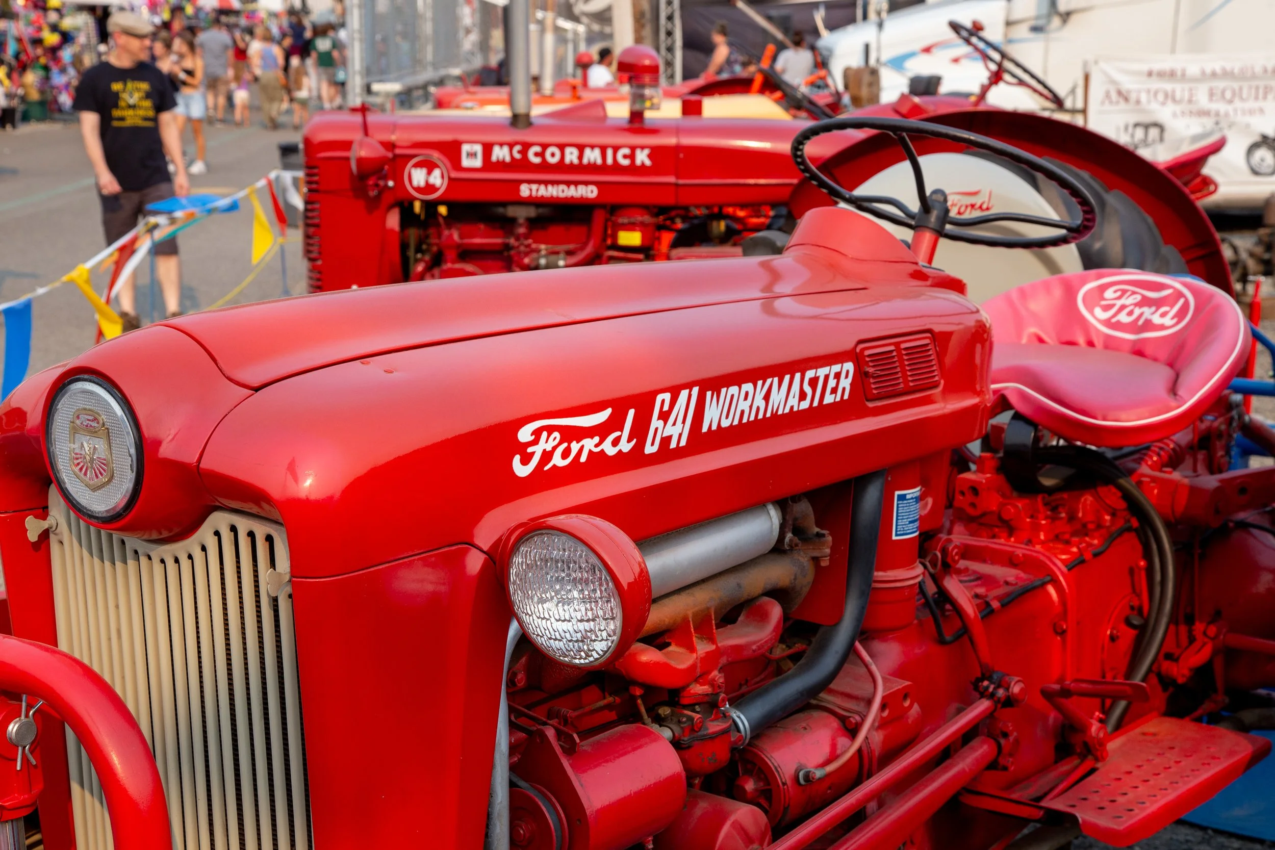 Red antique tractors lined up behind a rope at the Clark County Fair