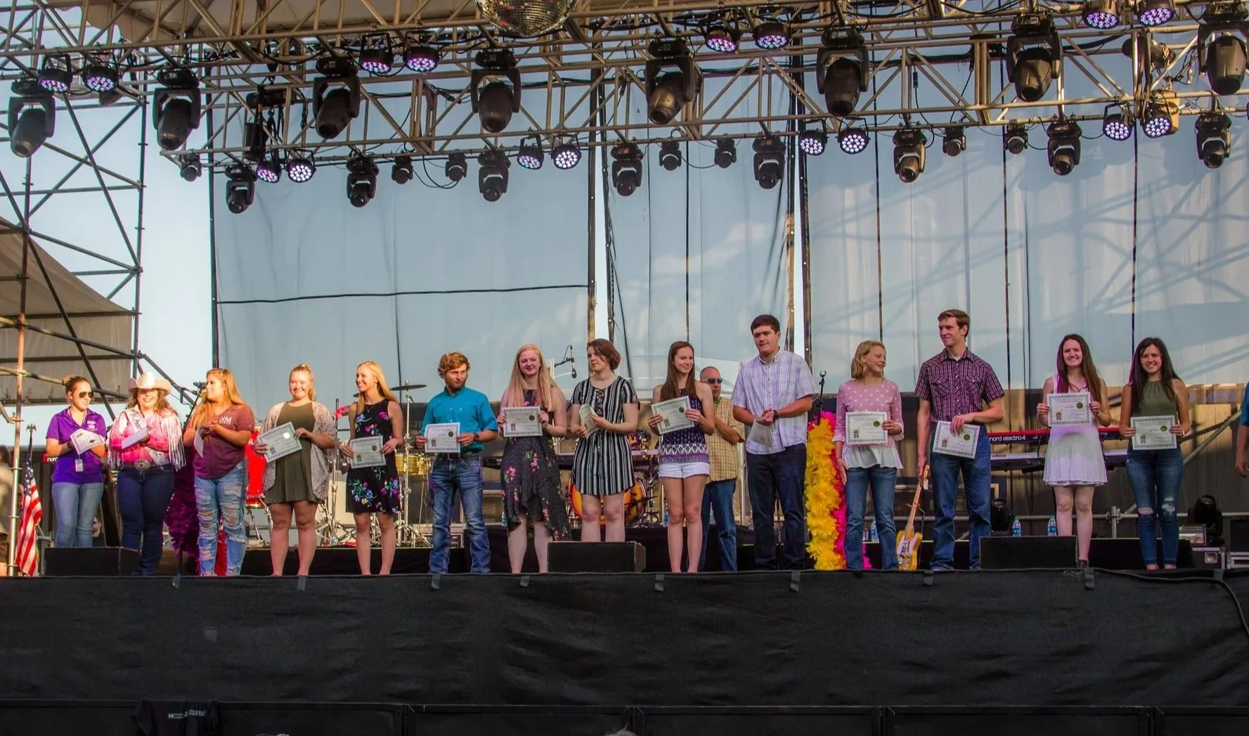 Clark County Fair Scholarship Award winners lined up across a stage holding certificates