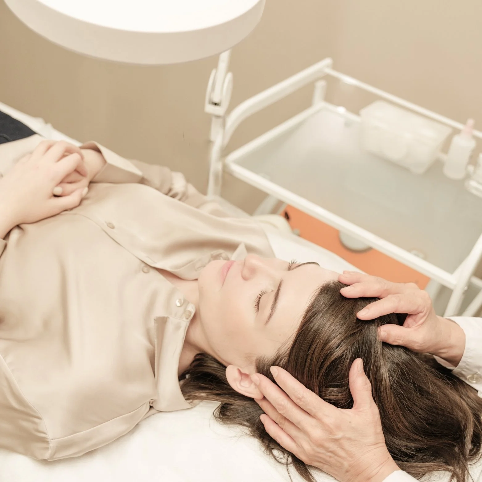 A person receiving a head massage or medical treatment while lying down in a clinical setting.