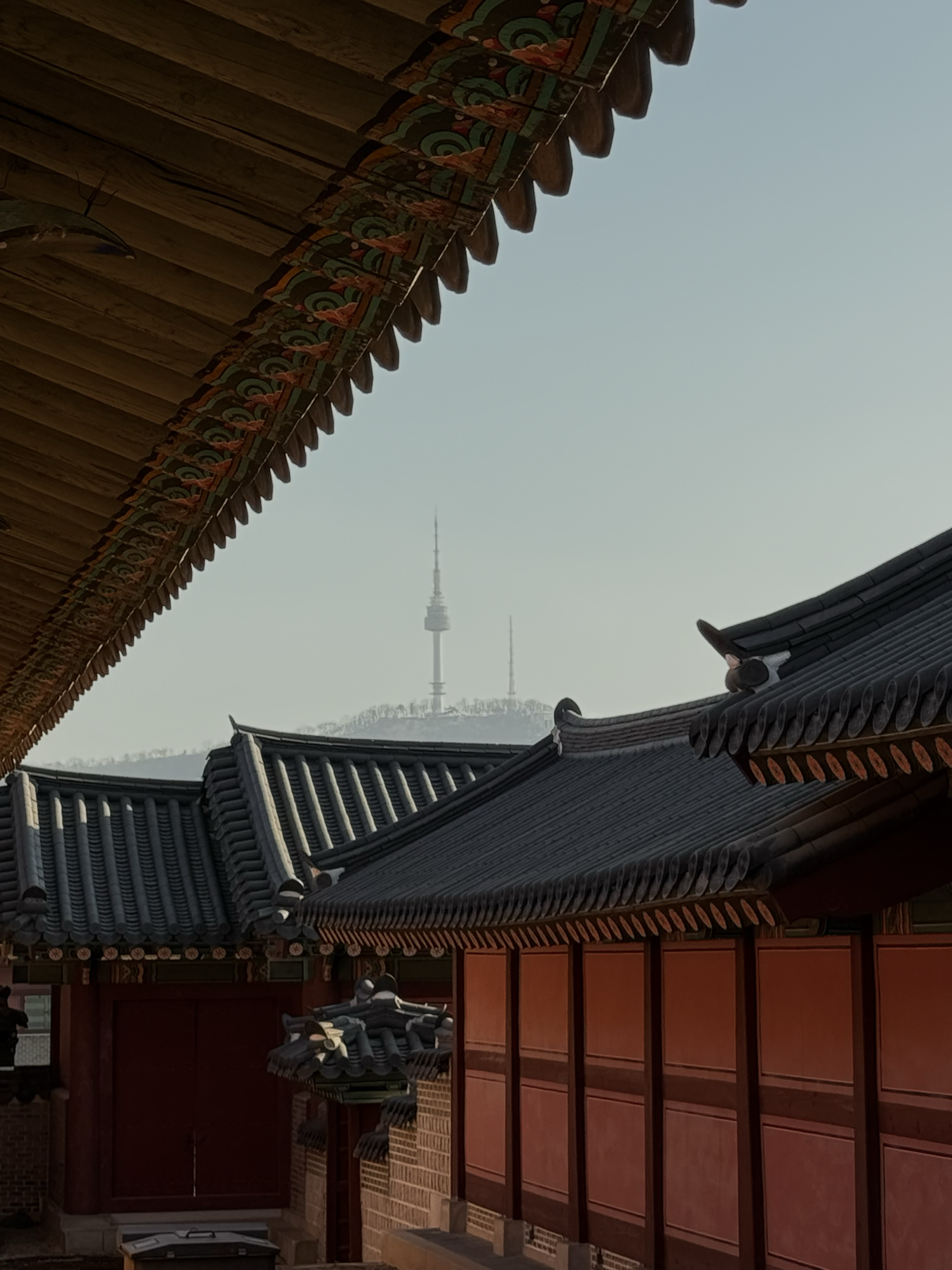 Vue de toits traditionnels coréens en bois et en tuiles, avec la Tour N de Séoul à l'arrière-plan.