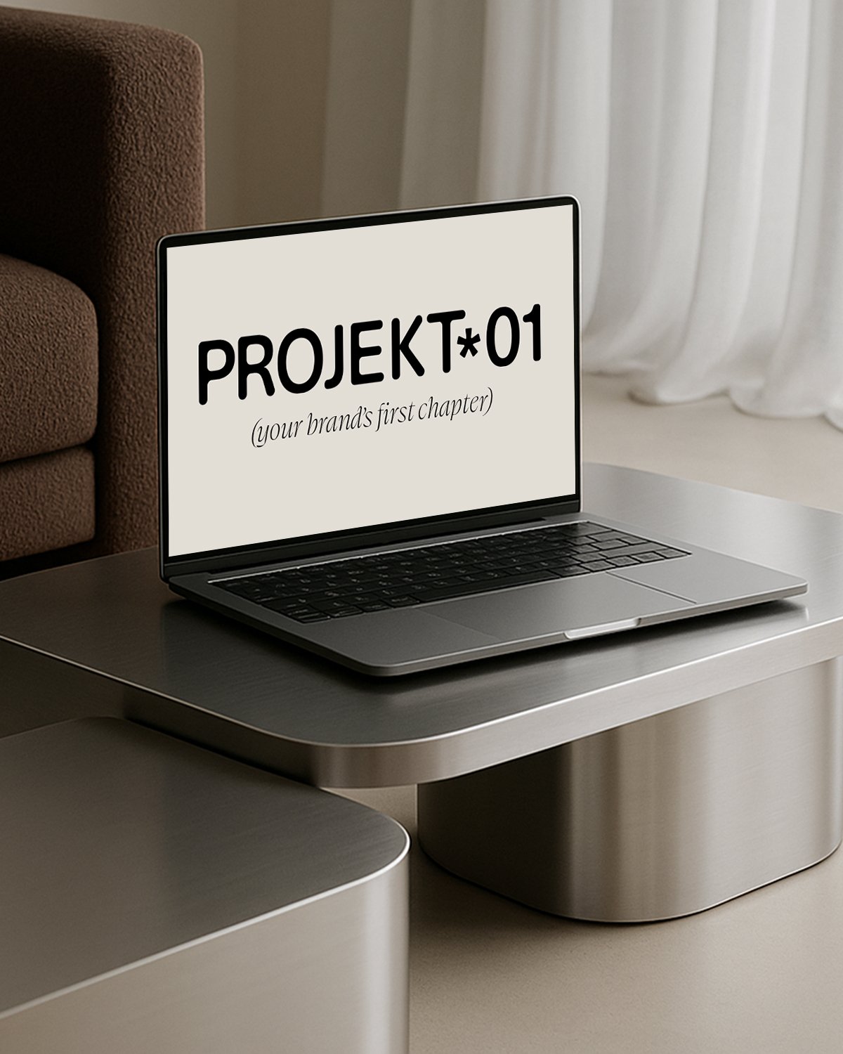 En bærbar computer på et bord med teksten 'PROJEKT 01 (your brand's first chapter)' på skærmen.