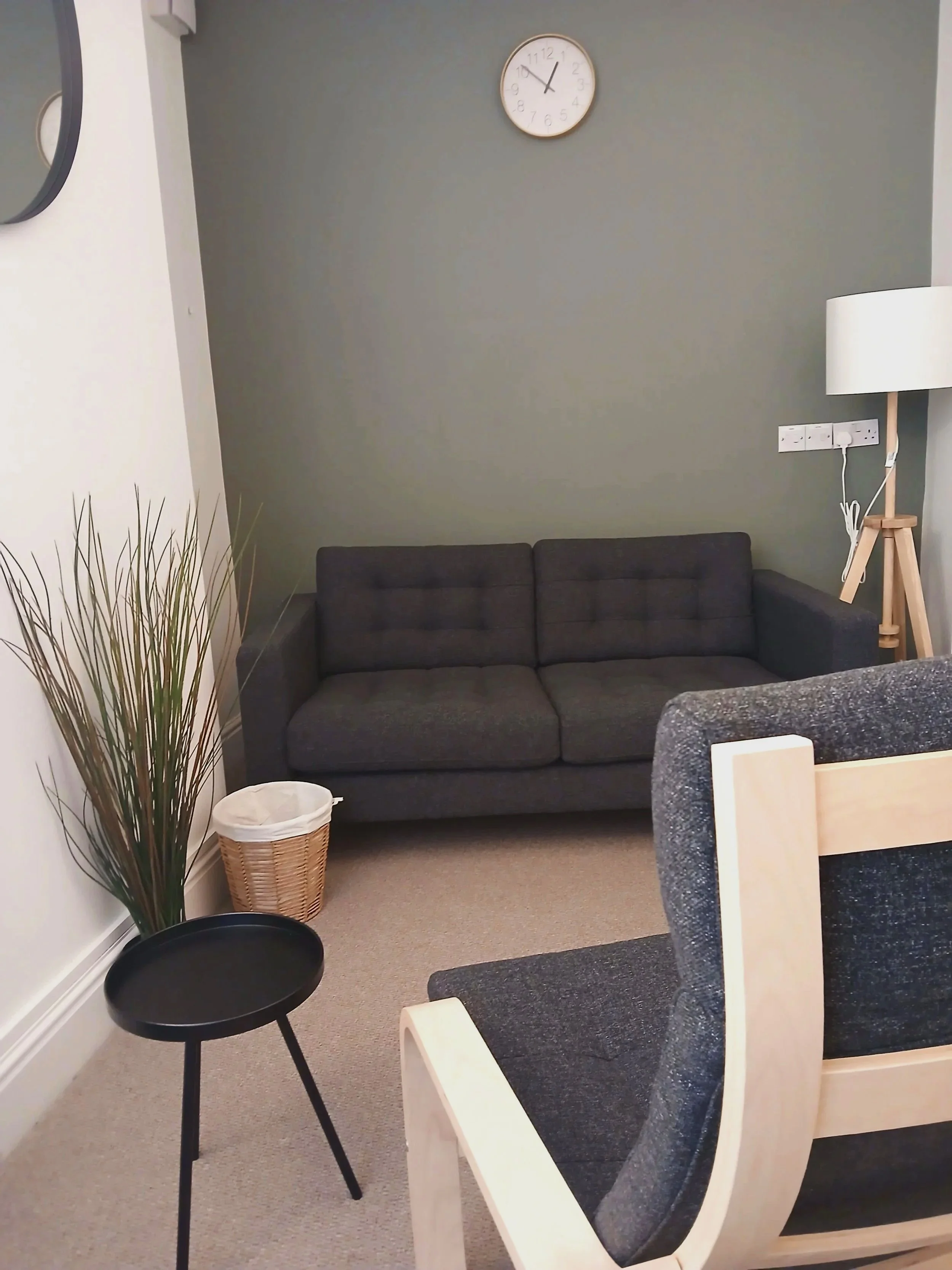 Modern wooden house with large glass window set against a mountainous landscape with grassy terrain and sparse trees.