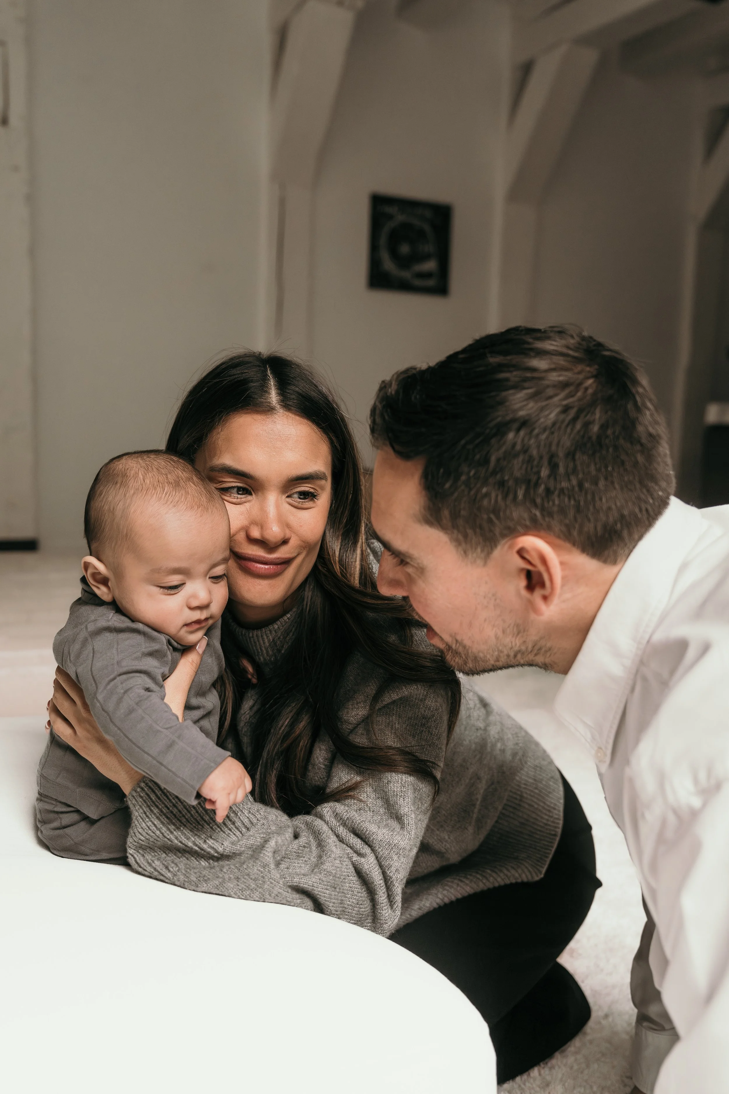 Familie met jong kind samen in een huis, contact maken en genieten van elkaar tijdens een new born shoot van Rosa Lynn Signer. 
