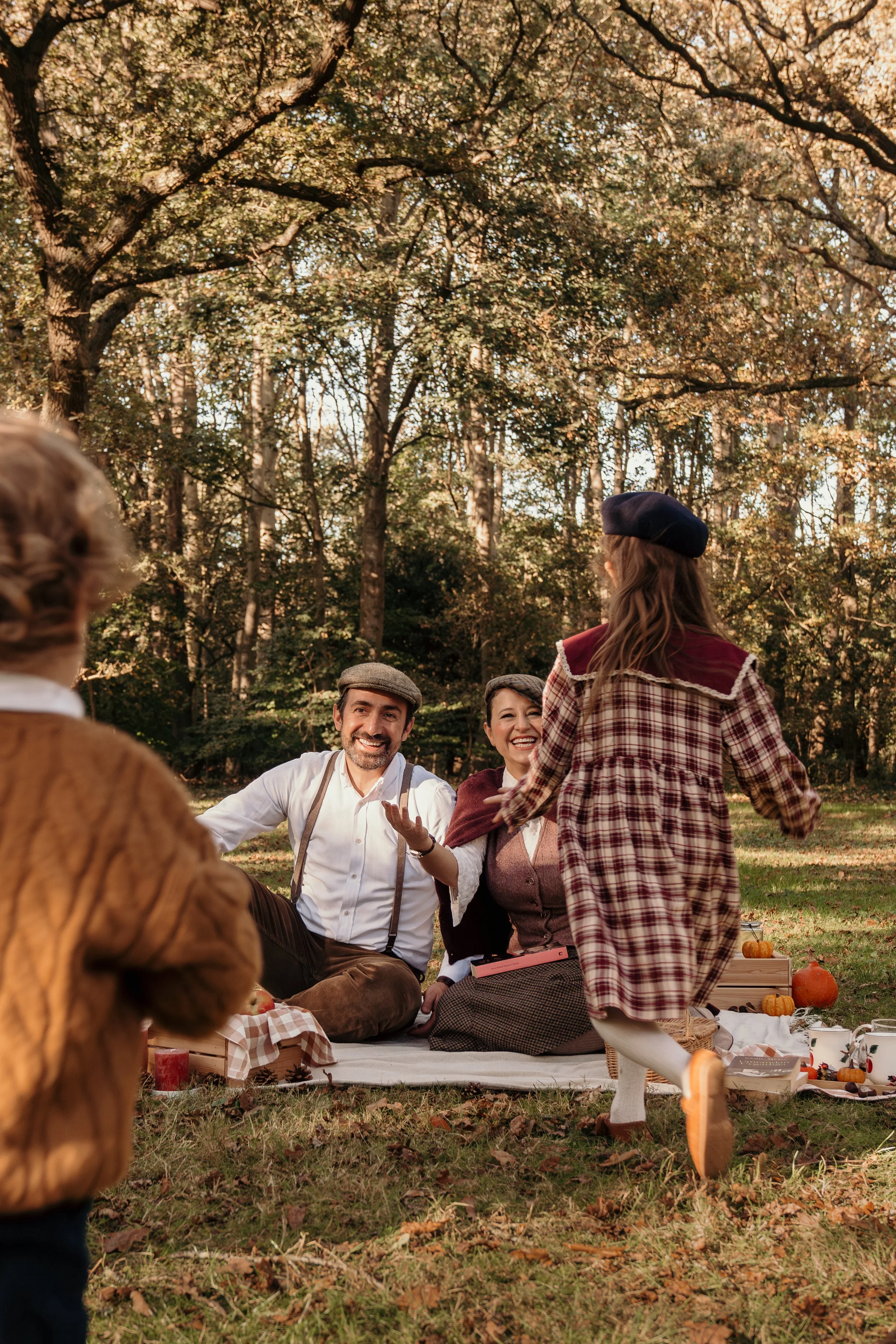 Gezin genietend van een picknick in het bos met herfstdecoraties en warme kleding tijdens een gezinsshoot van Rosa Lynn Signer.