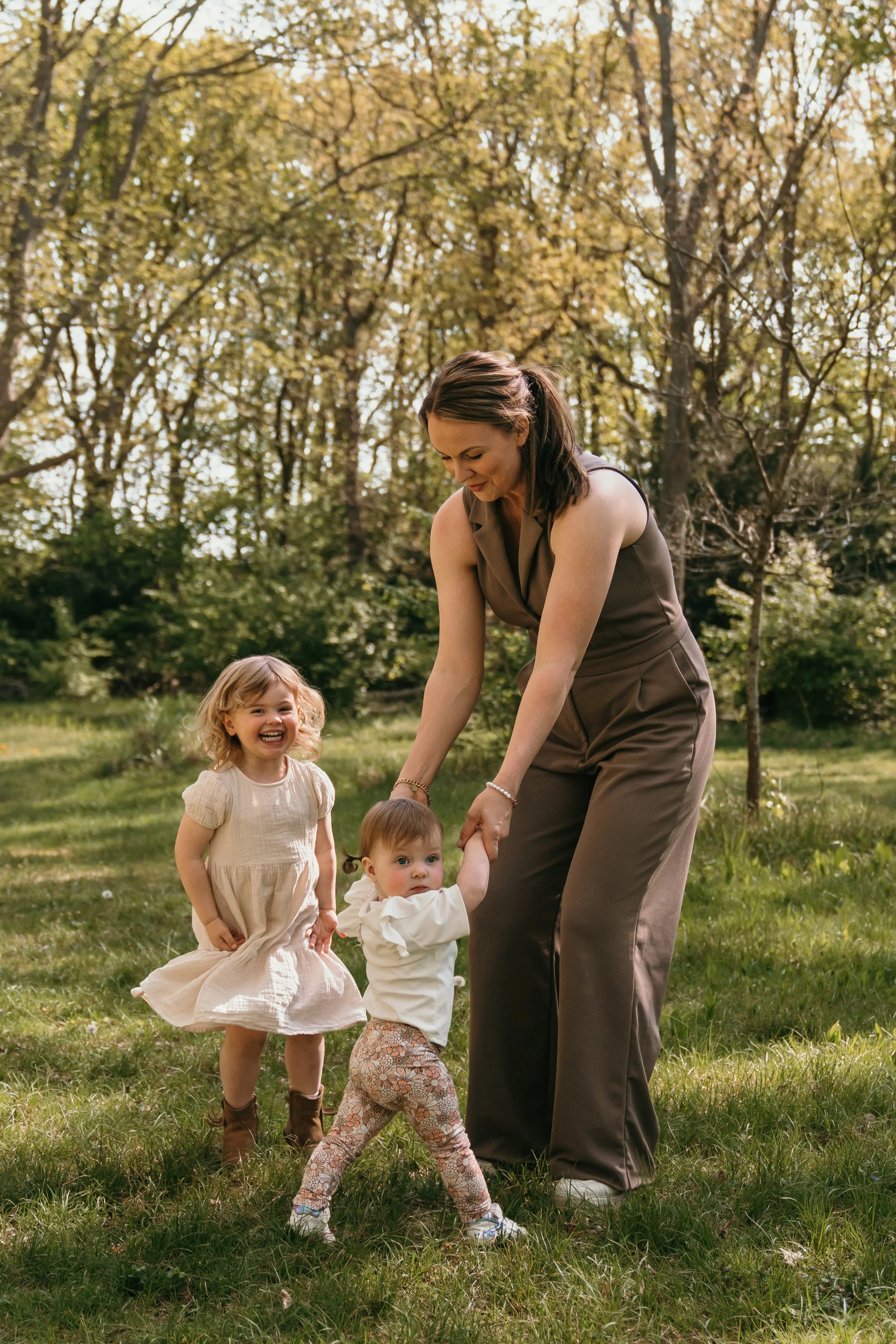 Moeder speelt met twee jonge kinderen in een park op een zonnige dag, omringd door groene bomen tijdens mommy & me minishoots van Rosa Lynn Signer. 